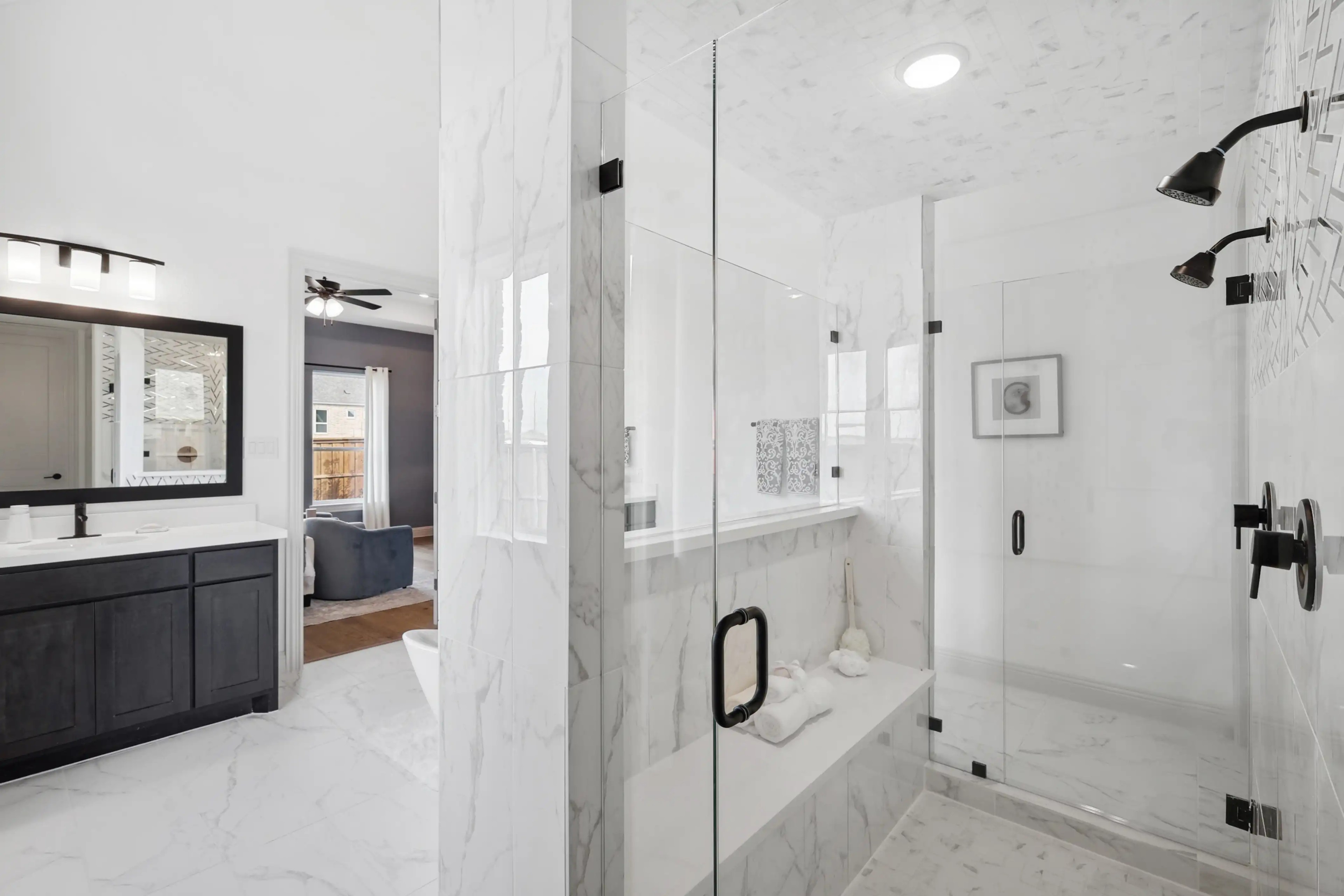Luxurious marble bathroom with glass shower, double vanity, dark wood cabinets in Westside Preserve.