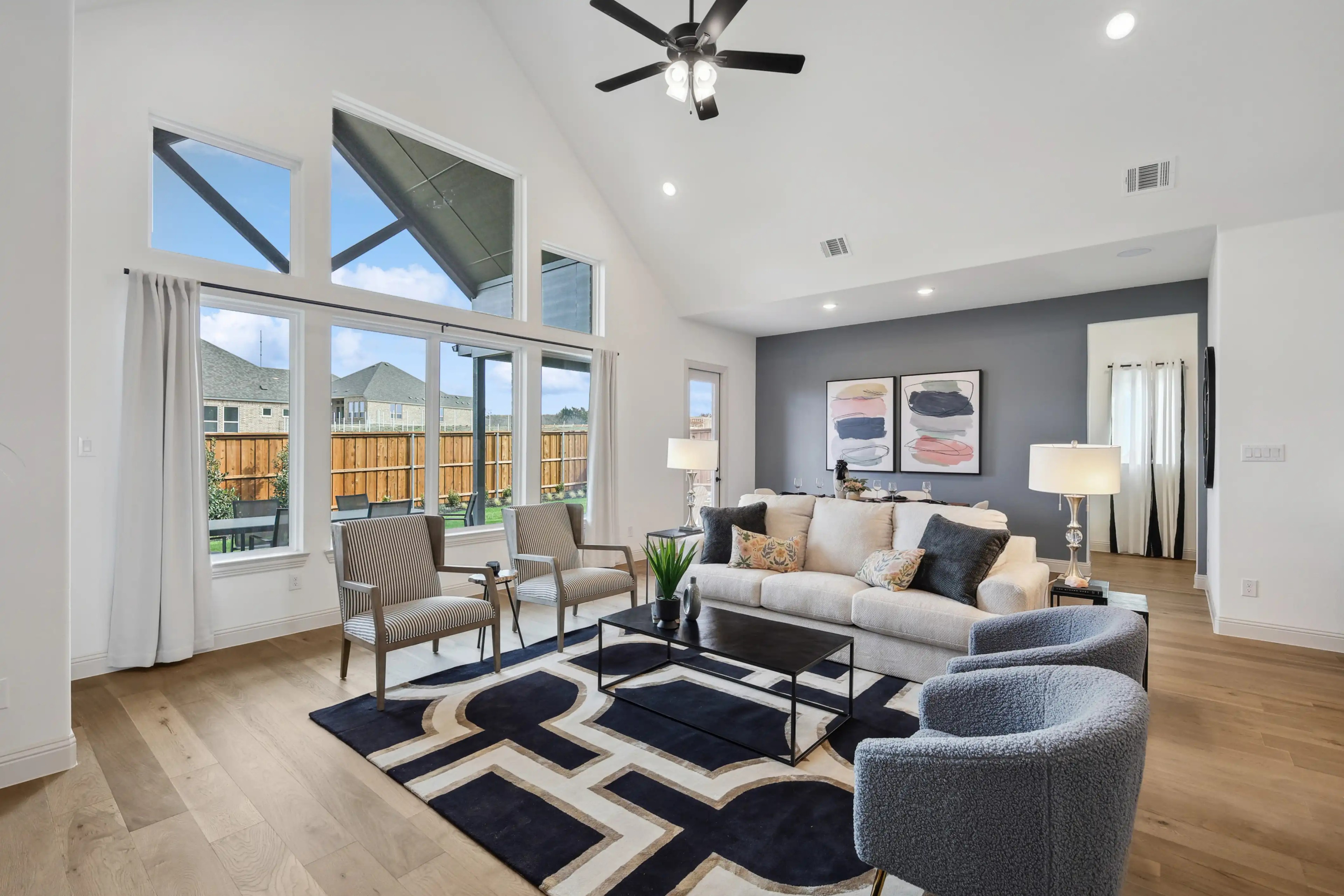 Modern Westside Preserve living room with high ceiling, large windows, elegant decor, hardwood floors.
