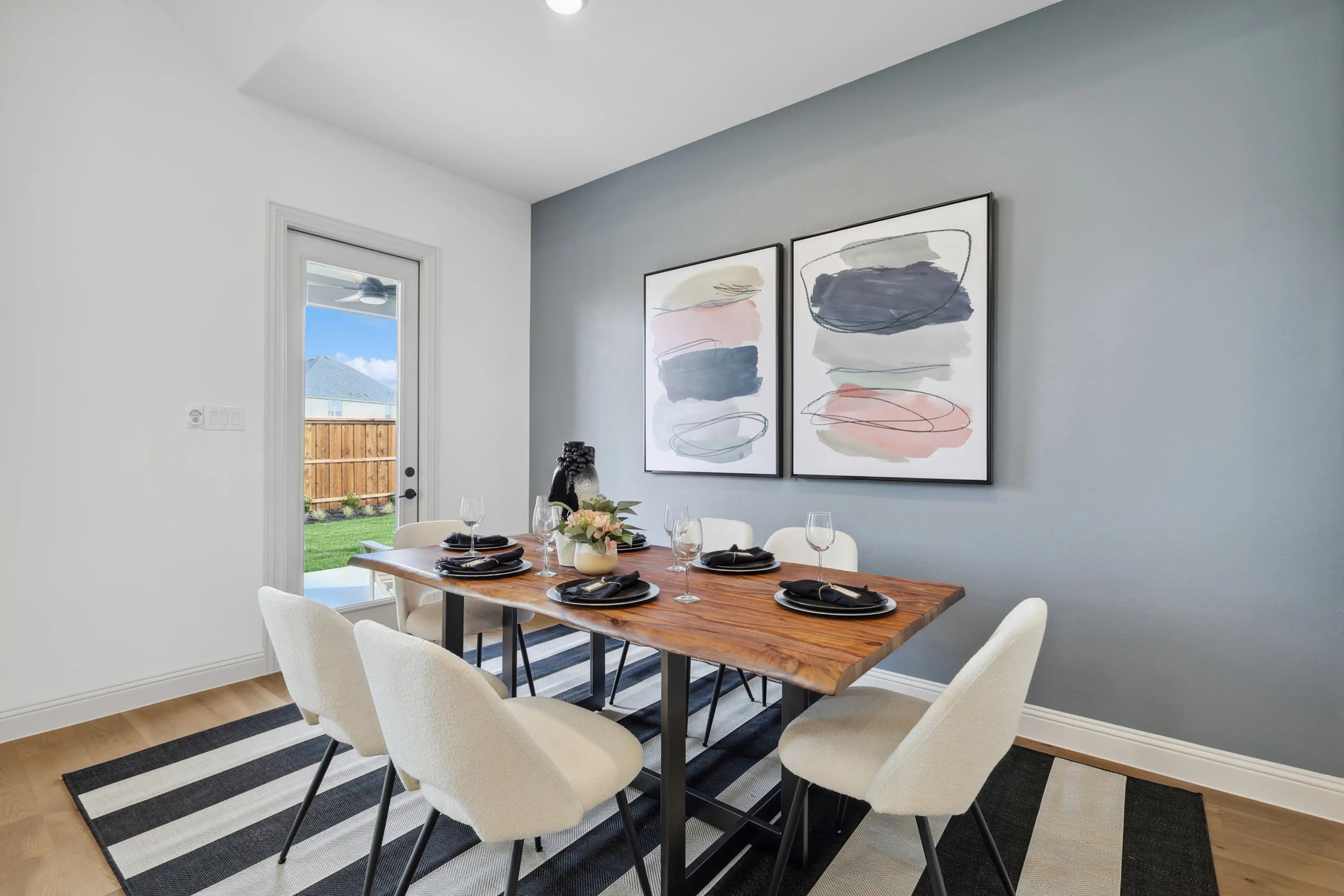 Elegant dining area with wooden table, abstract art, and outdoor view in Westside Preserve home.