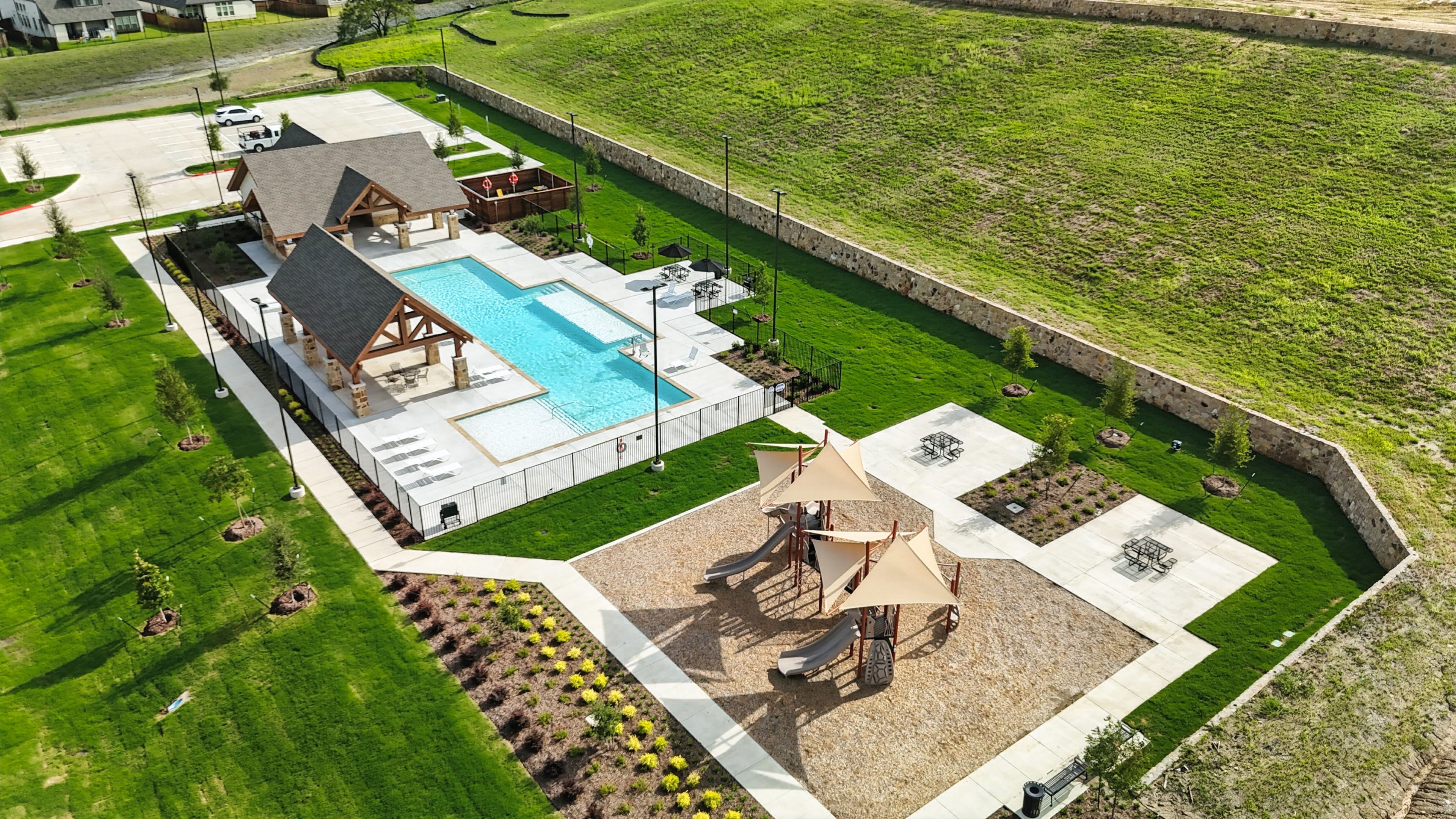 Aerial view of Westside Preserve amenities: pool with stone pavilion, playground, lush landscaping, and walking paths.