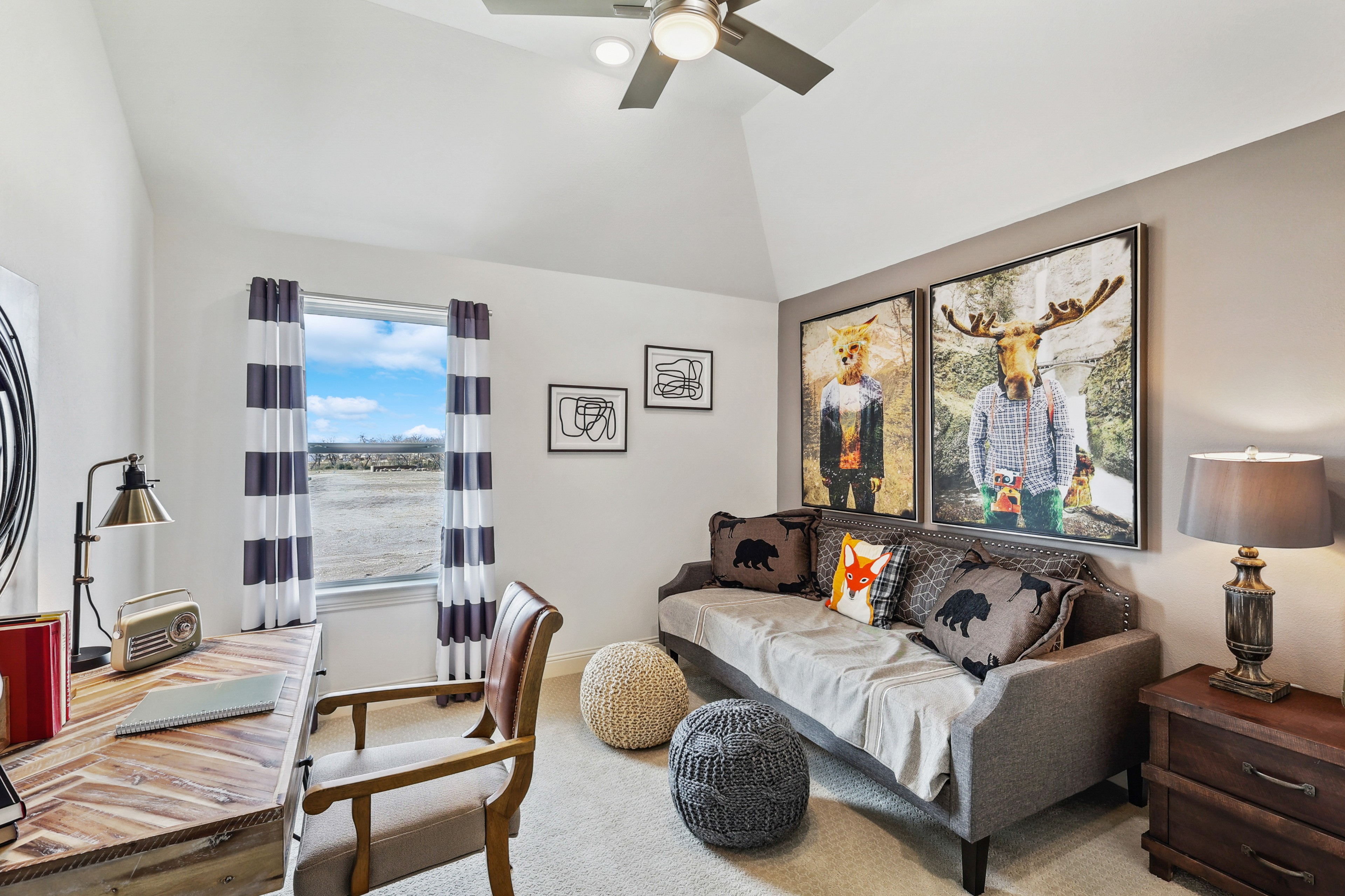 Cozy Texas study room with rustic desk, plush sofa, playful art, vibrant views. Solterra community home design.
