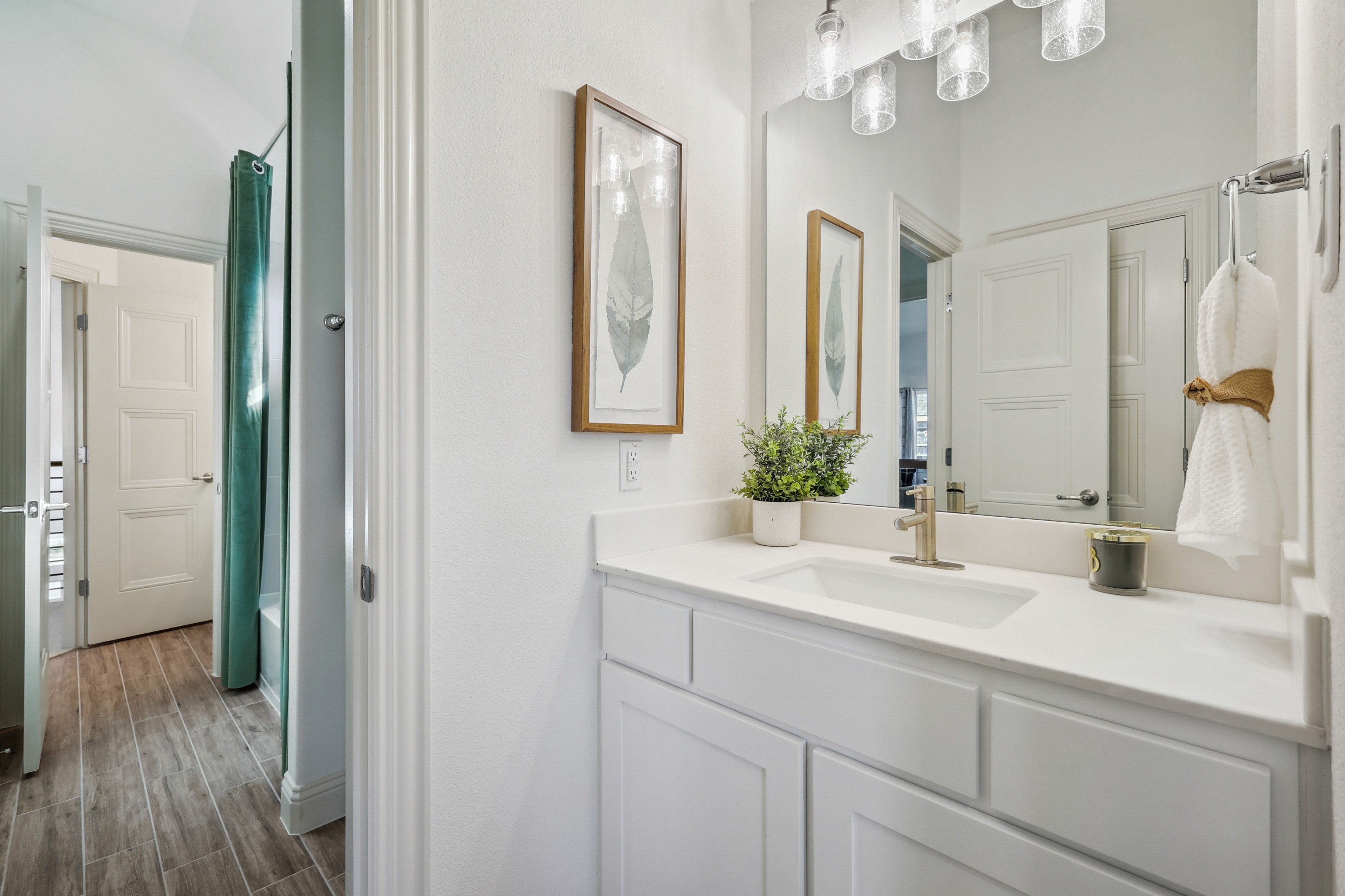 Modern bathroom vanity with white cabinetry, quartz countertop, and elegant lighting in Solterra Texas home.