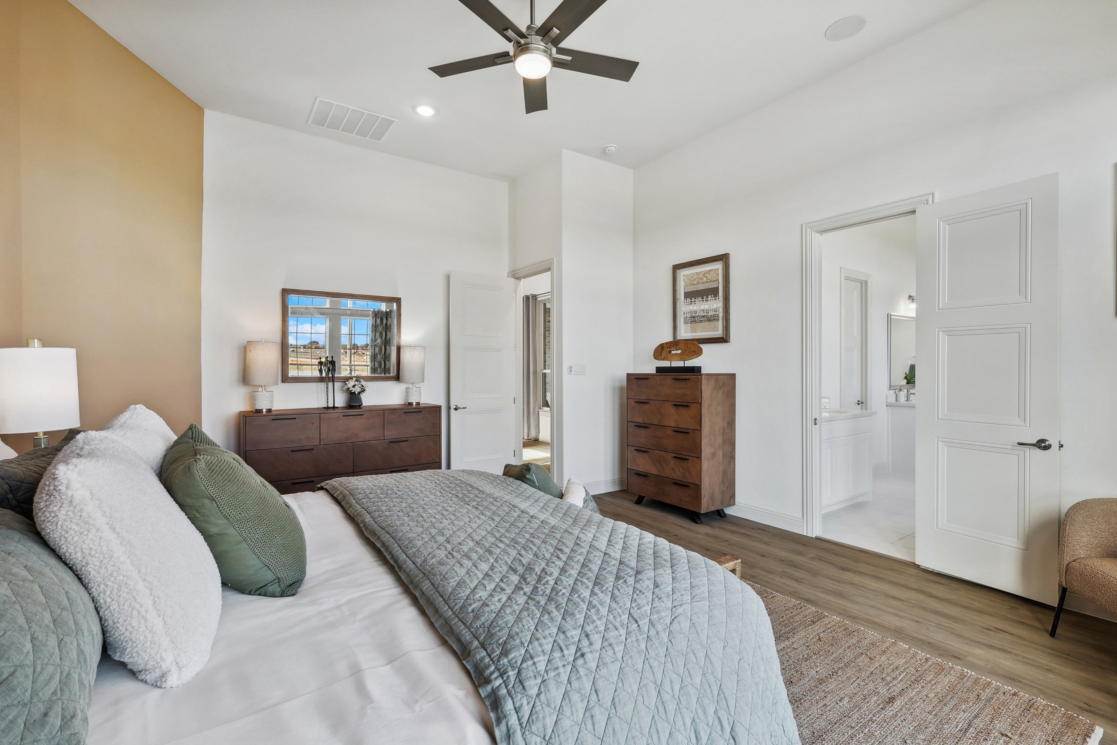 Modern bedroom in Solterra, Texas, featuring wood flooring, neutral tones, large window, and ceiling fan.