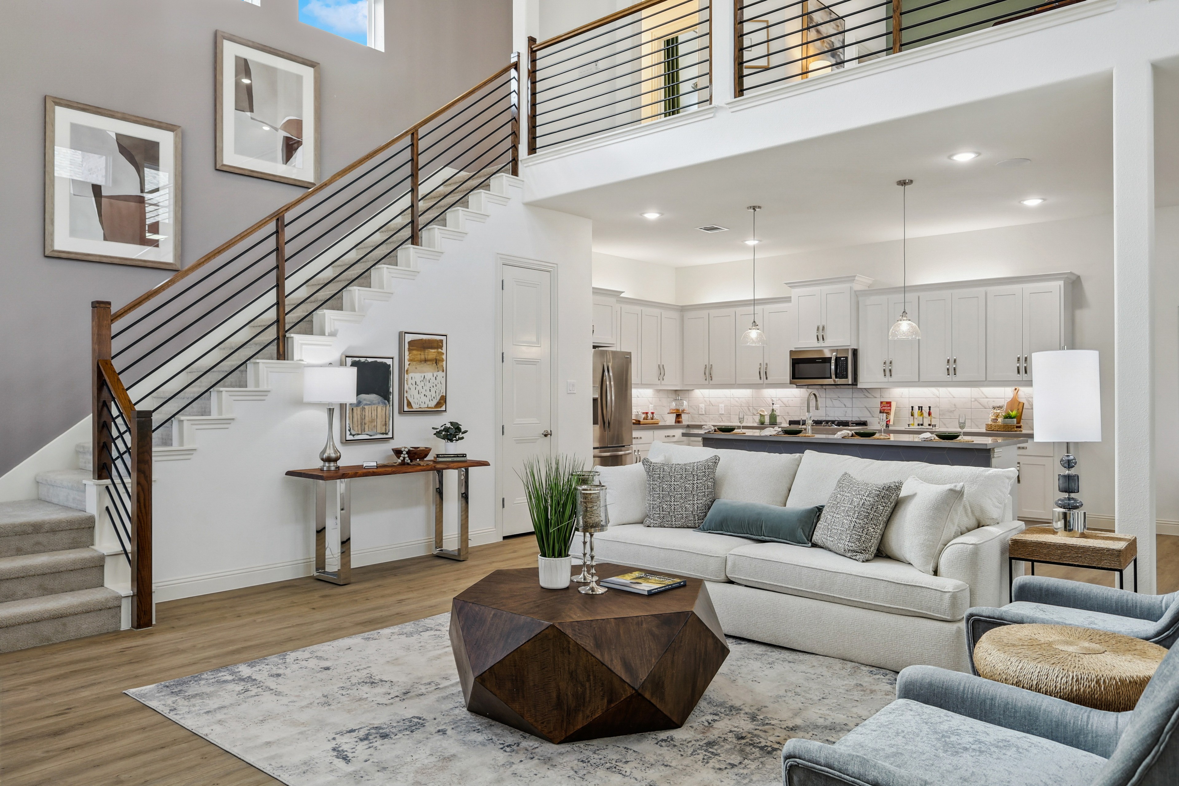 Spacious Solterra Texas living room, modern kitchen, elegant staircase with wood railing, large windows.