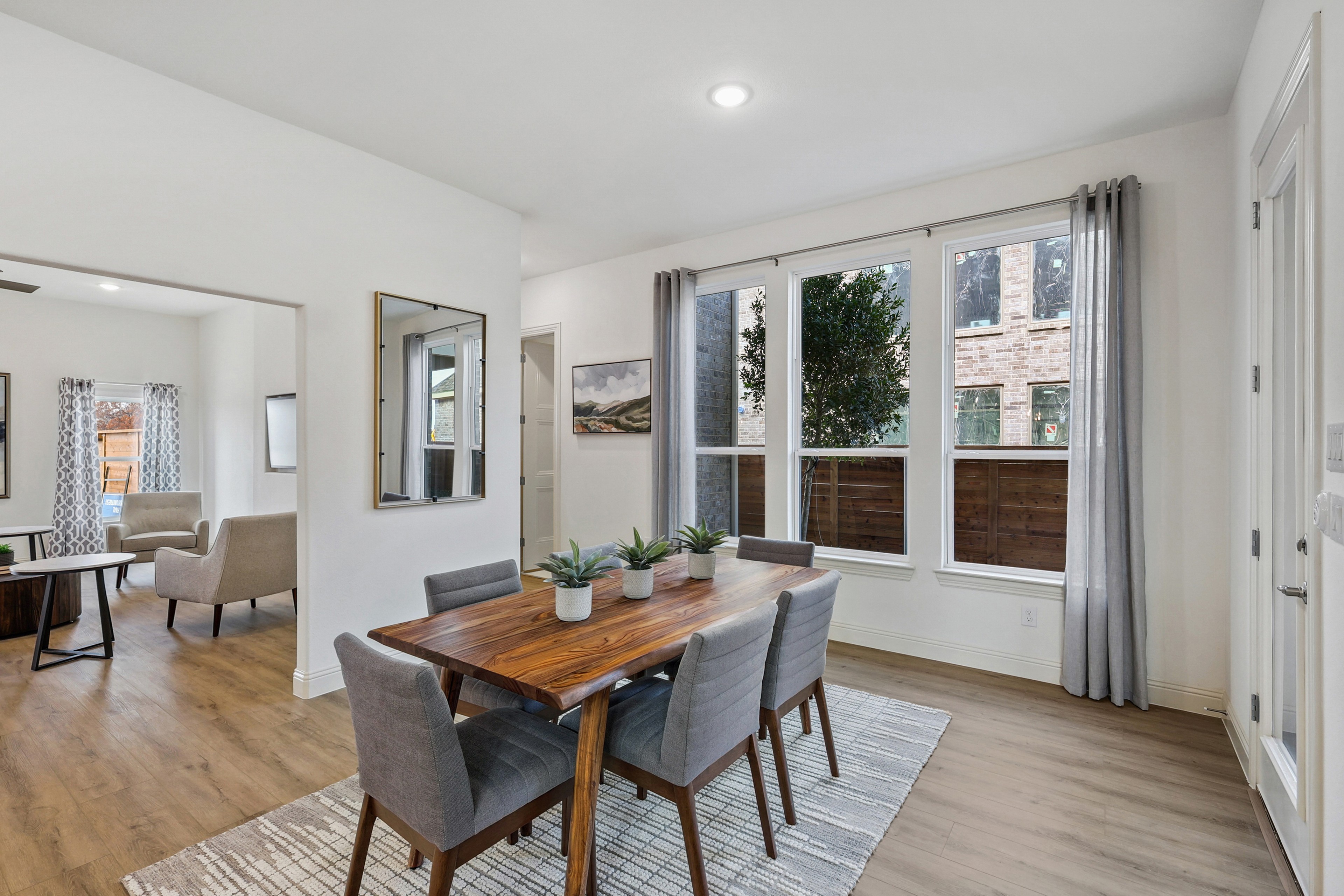 Elegant dining room with large windows, hardwood floors, and contemporary decor in Solterra, Texas.