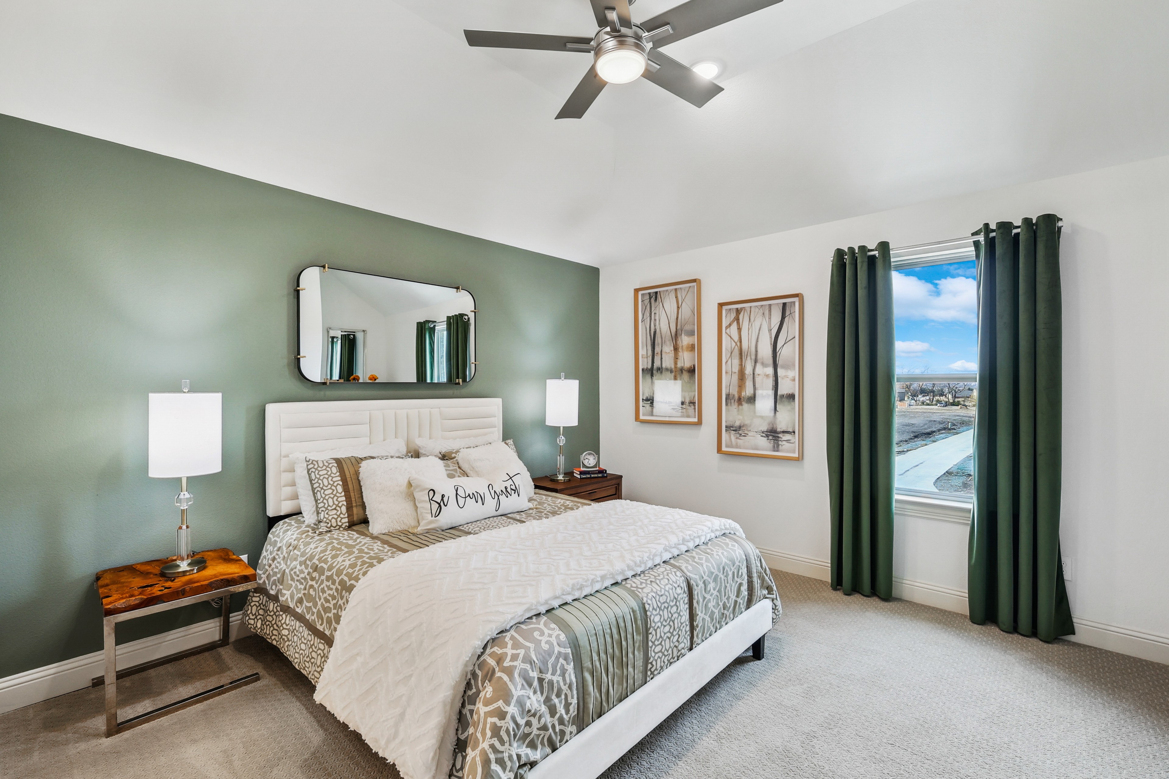 Luxurious bedroom with green accent wall, large window, stylish decor in Solterra Texas community.
