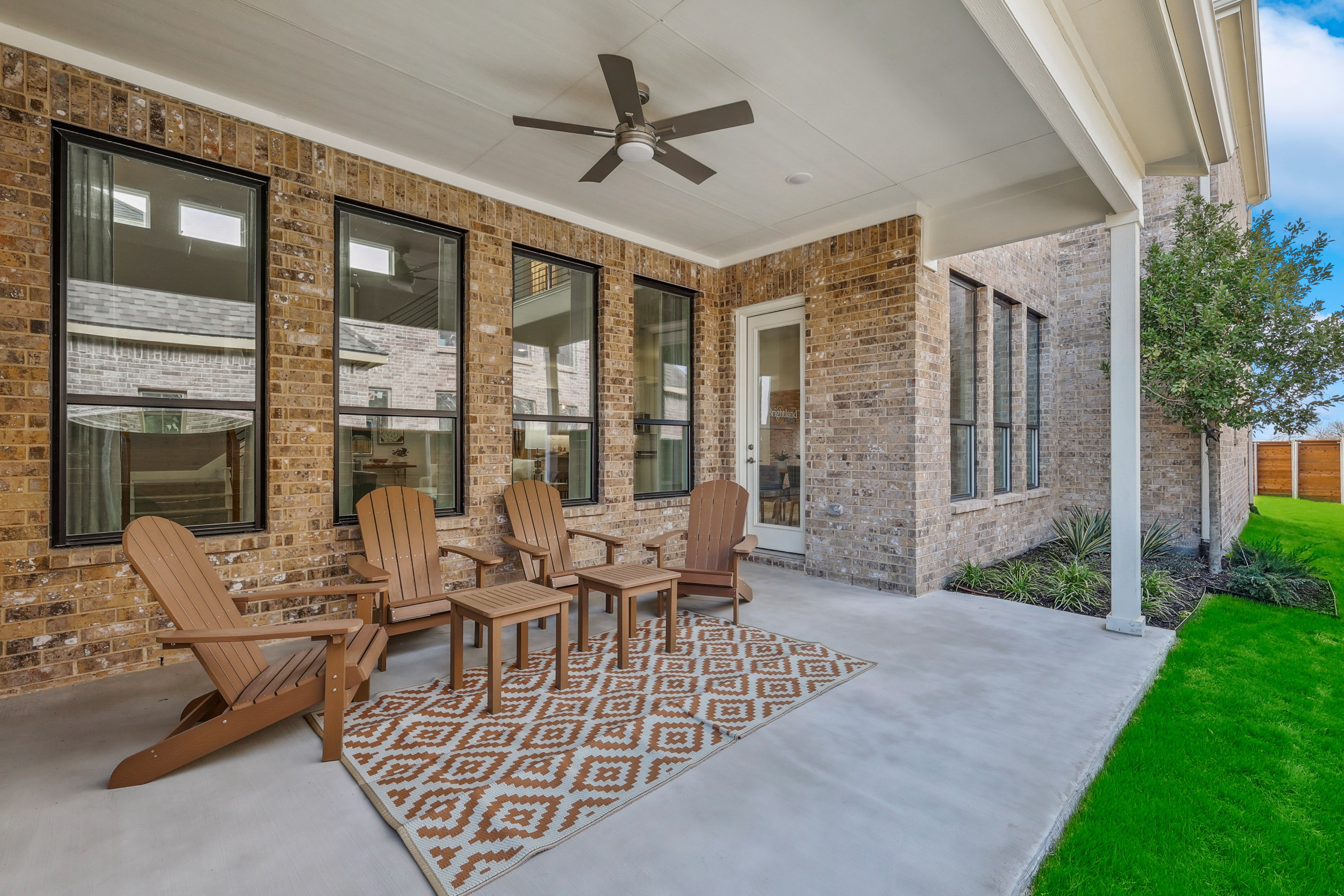 Covered patio with Adirondack chairs, brick walls, ceiling fan in Solterra, Texas. Modern outdoor space.