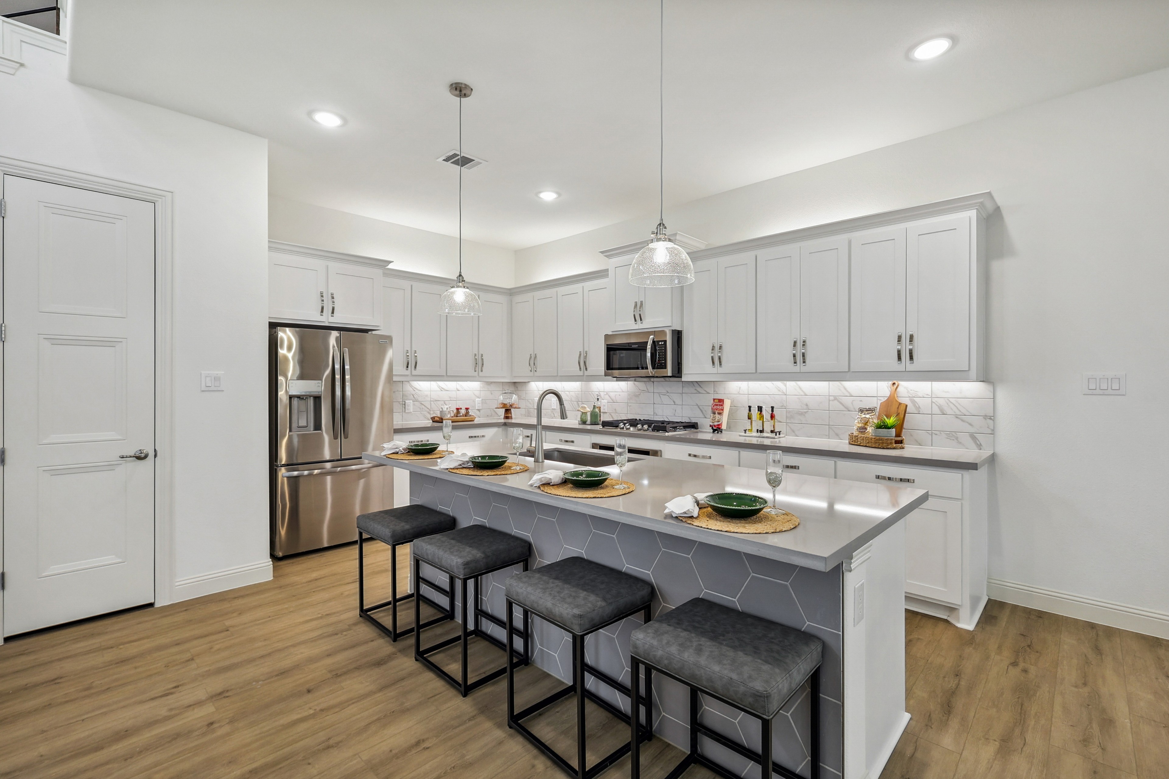 Modern kitchen with pendant lights, island seating, white cabinets, stainless steel appliances. Solterra, Texas.