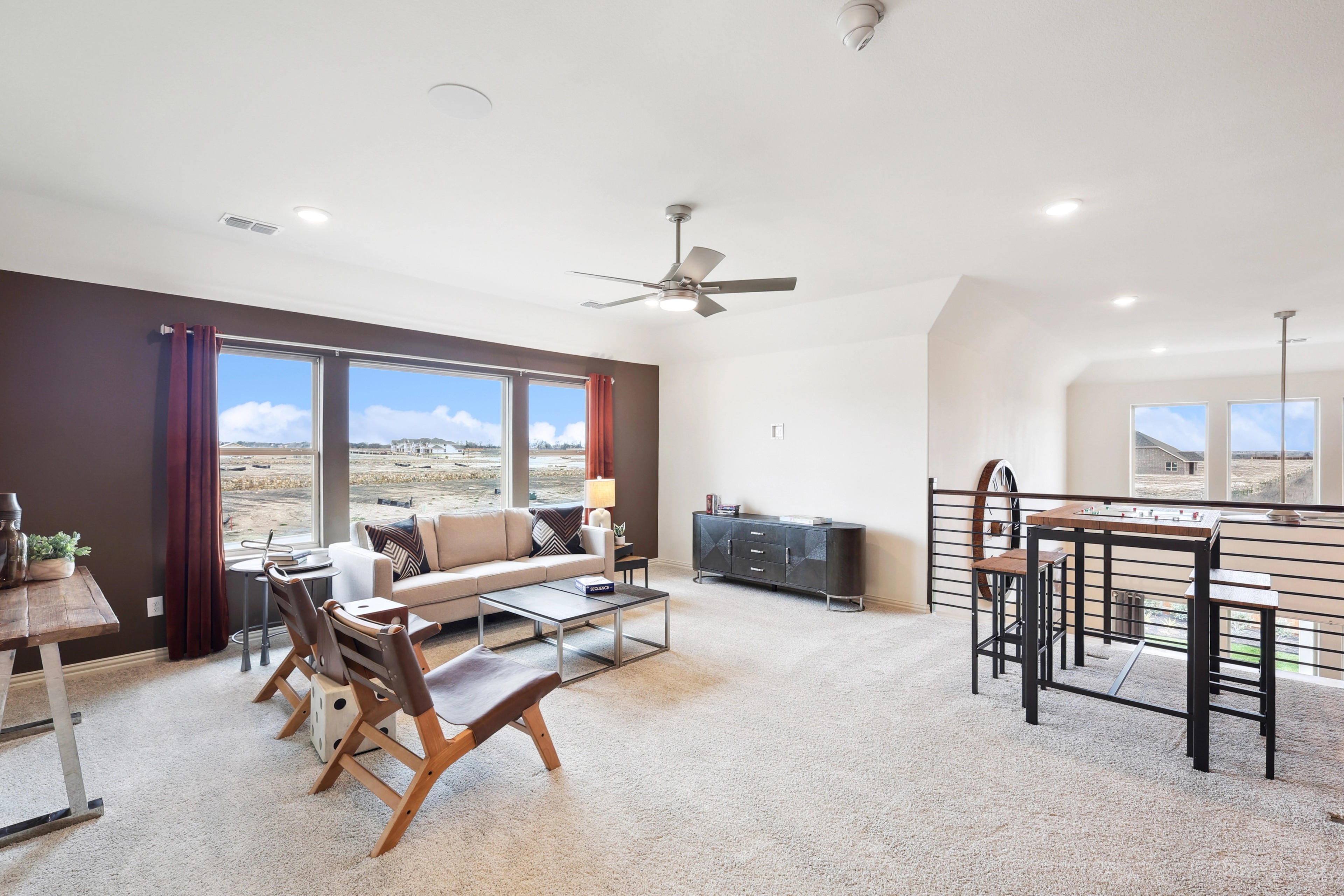 Modern living room with large windows, stylish furniture, and open layout in The Oaks community.