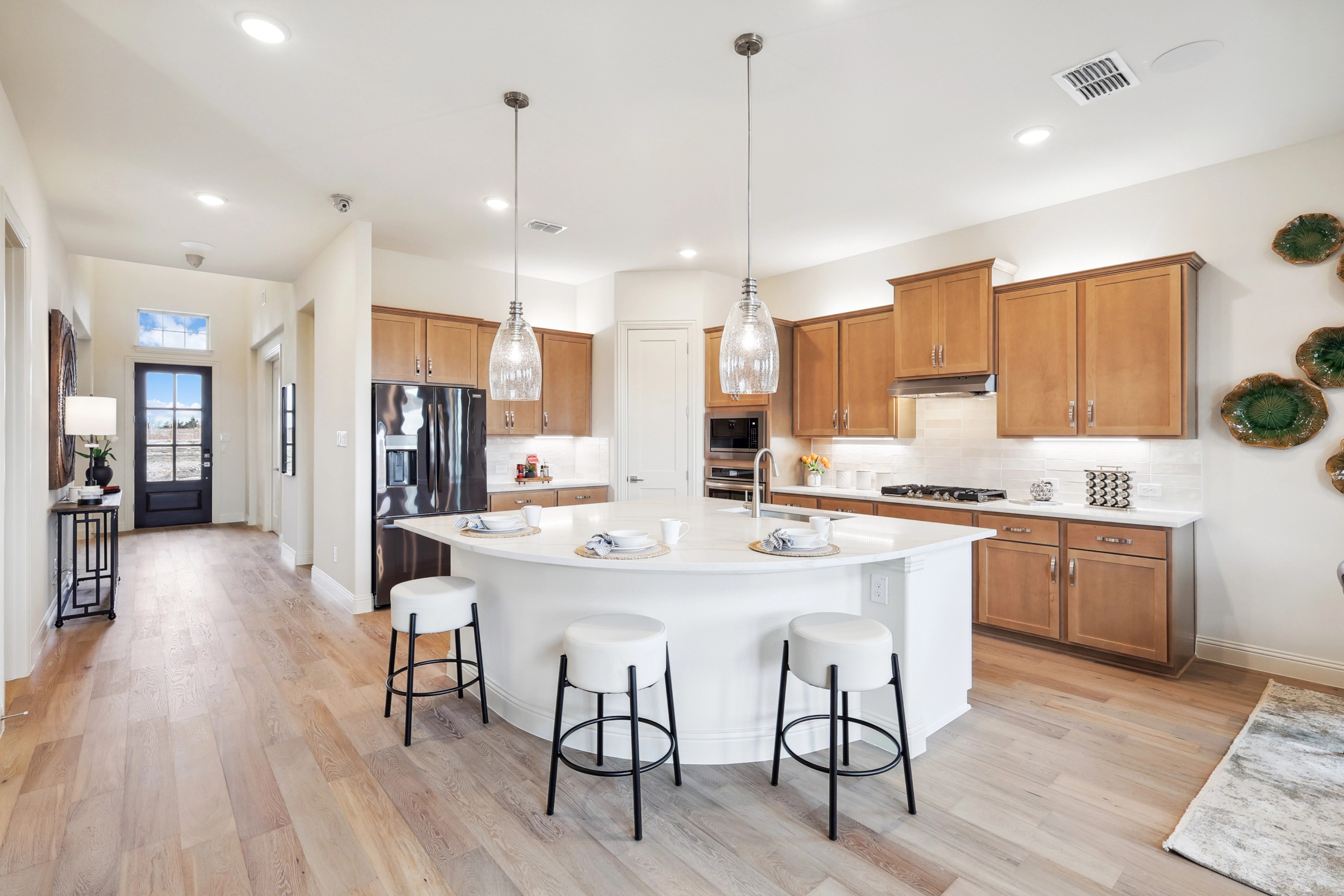 Modern kitchen with pendant lighting, wood floors, and center island at The Oaks community.