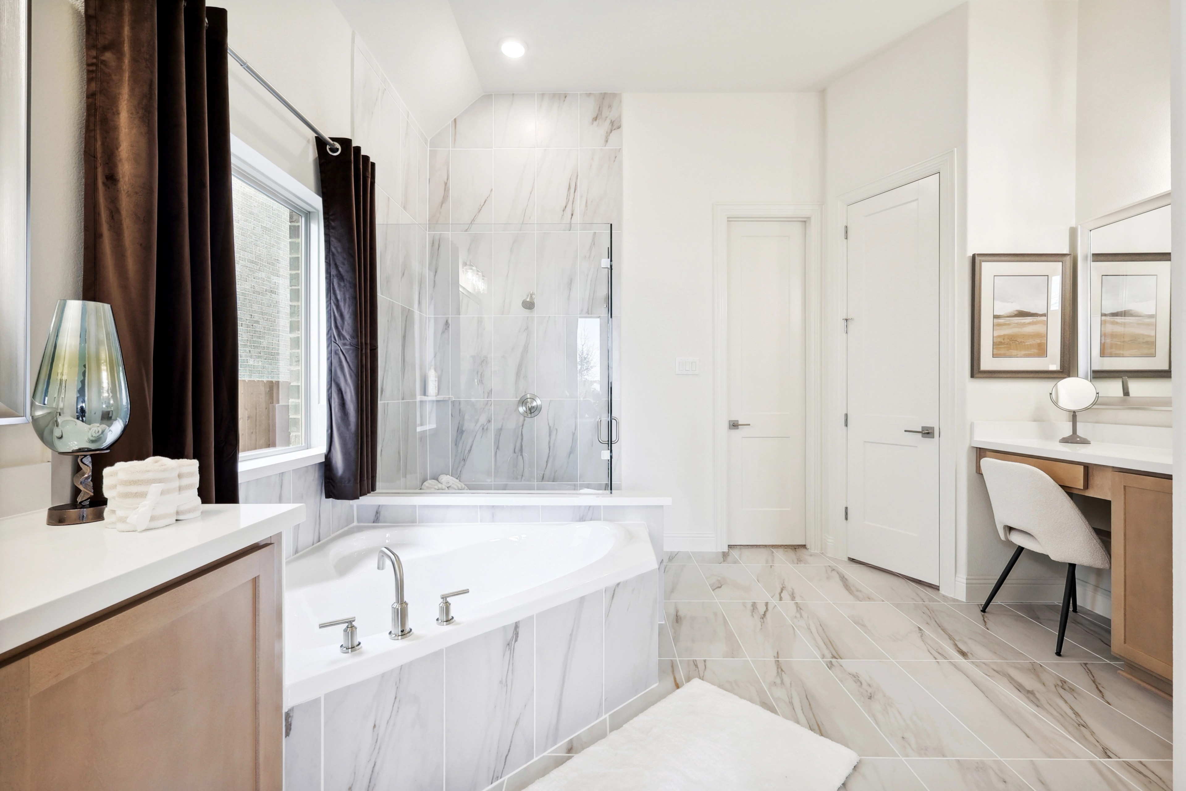 Luxurious bathroom with marble tiles, glass shower, soaking tub, and vanity. The Oaks community.