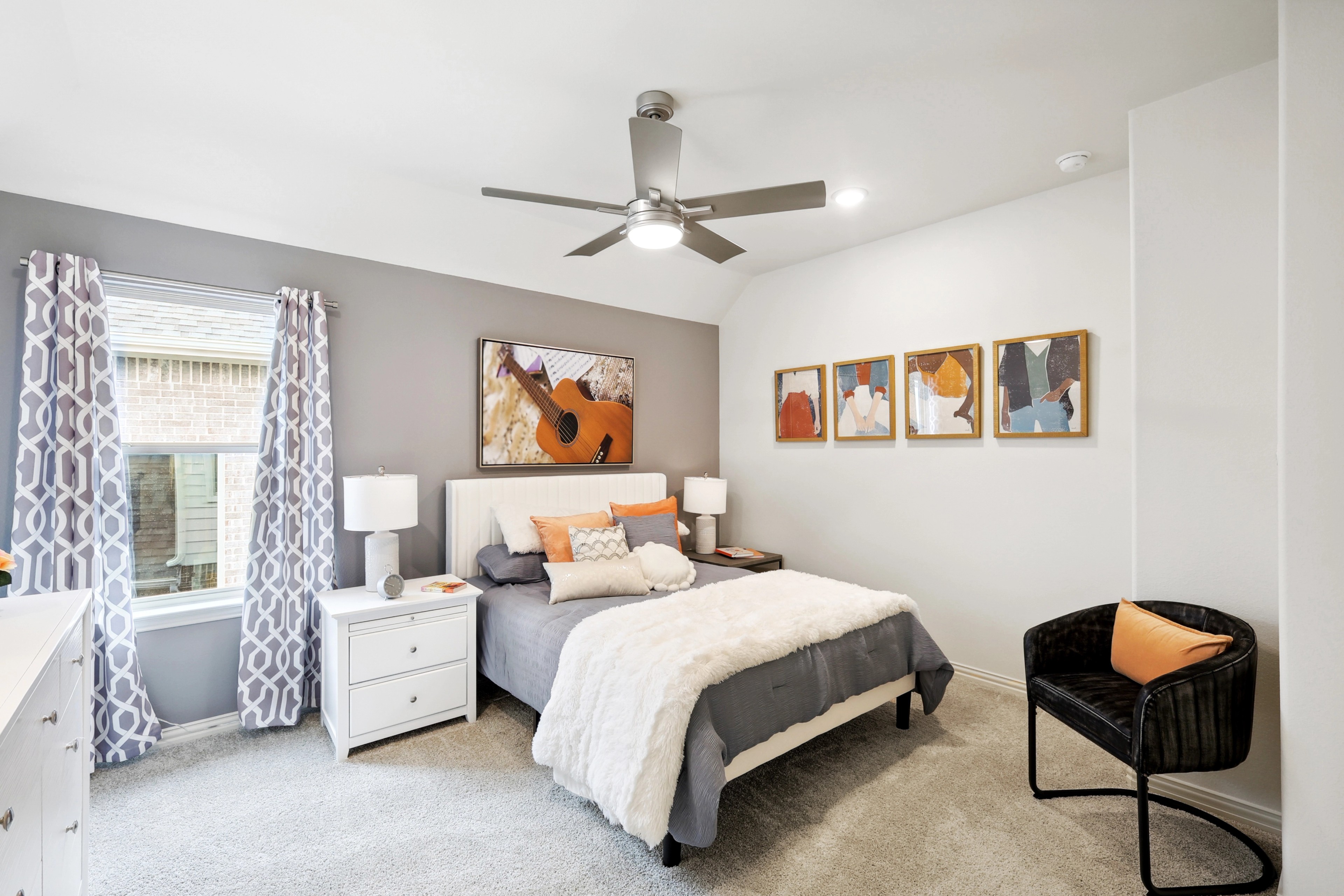 Modern bedroom with elegant decor, featuring a stylish ceiling fan, plush bedding, and vibrant artwork, The Oaks.