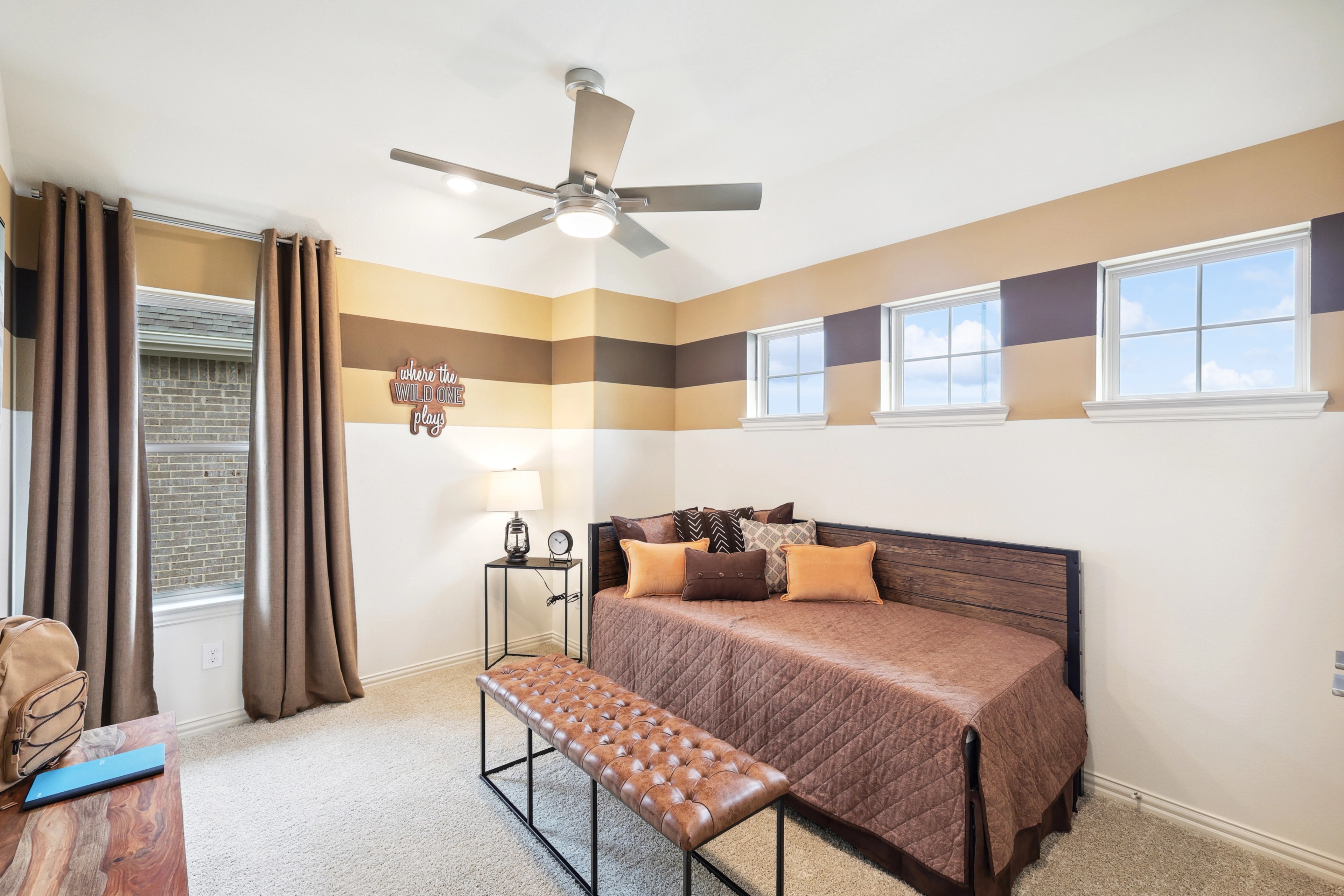 Cozy bedroom with striped walls, ceiling fan, and elegant decor in The Oaks community.