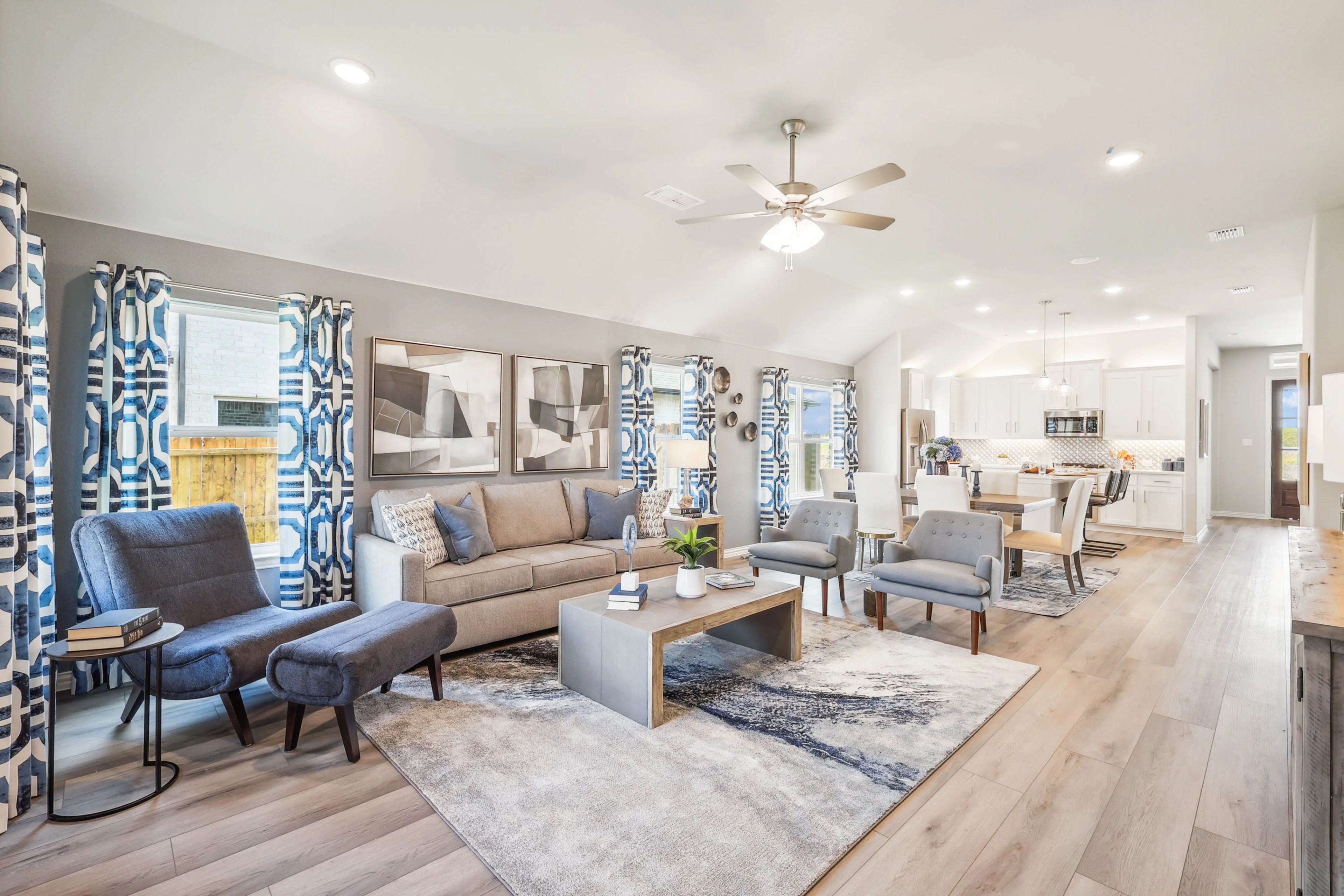 Spacious Pebblebrook living room with modern decor, open-plan kitchen, gray sofas, and patterned curtains.