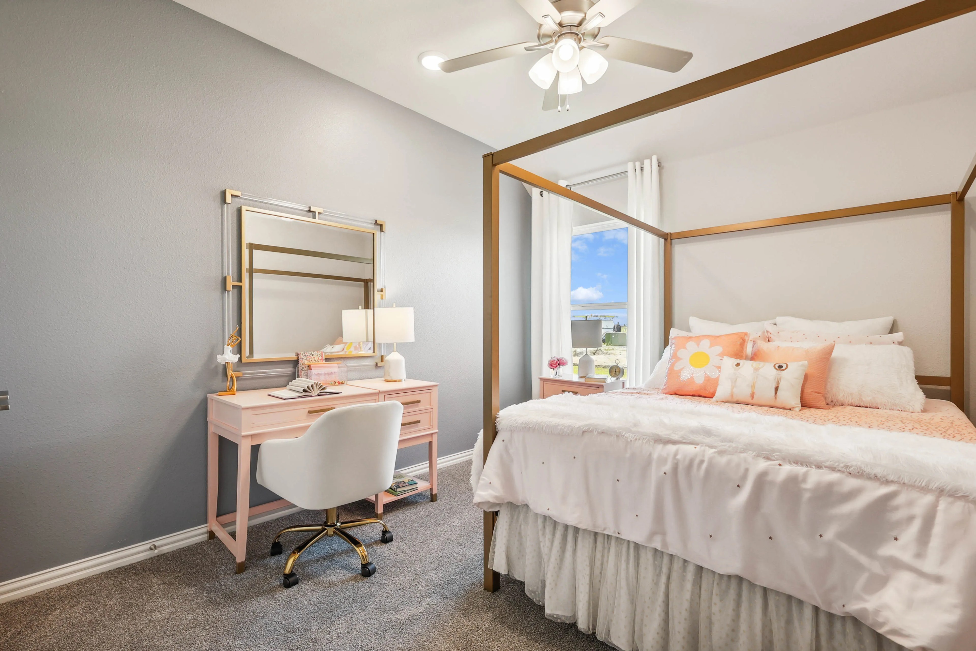 Chic bedroom in Pebblebrook, with luxe pink vanity, gold mirror, plush bedding, elegant ceiling fan, abundant natural light.