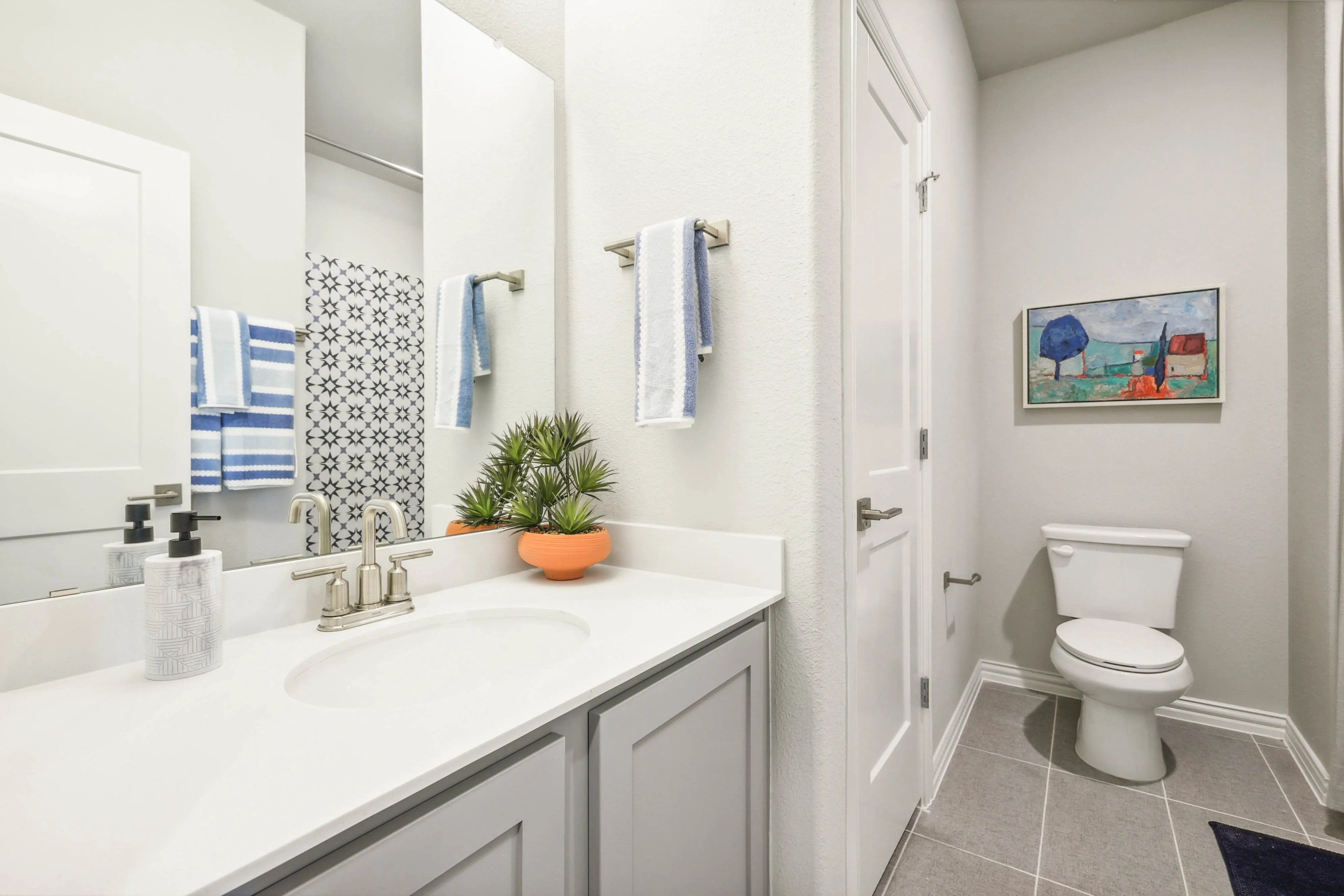 Modern bathroom with white vanity, stylish faucet, wall art, gray tiles in Pebblebrook community. Elegant design.