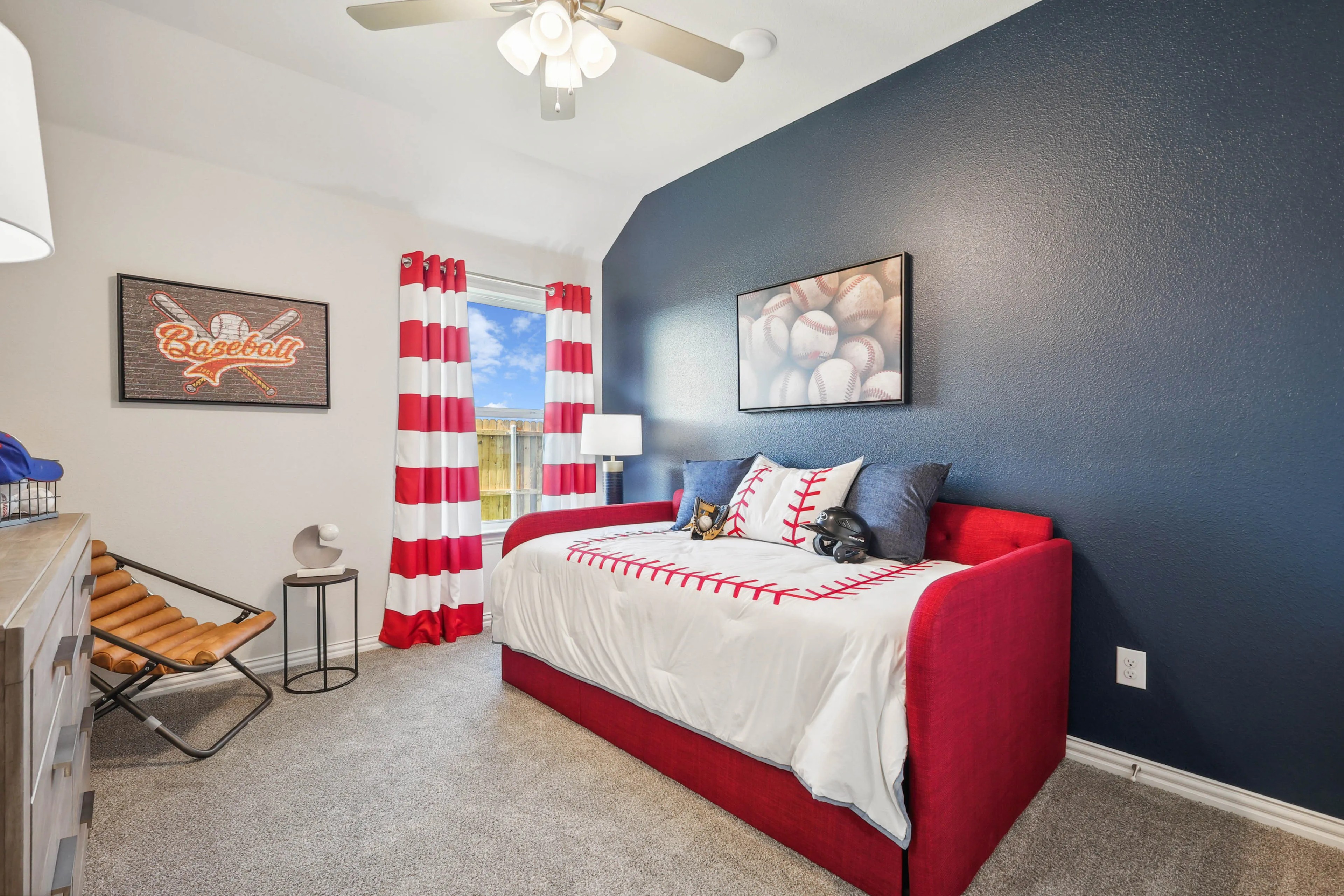 Baseball-themed bedroom with a red daybed, striped curtains, and sports decor in Pebblebrook community.