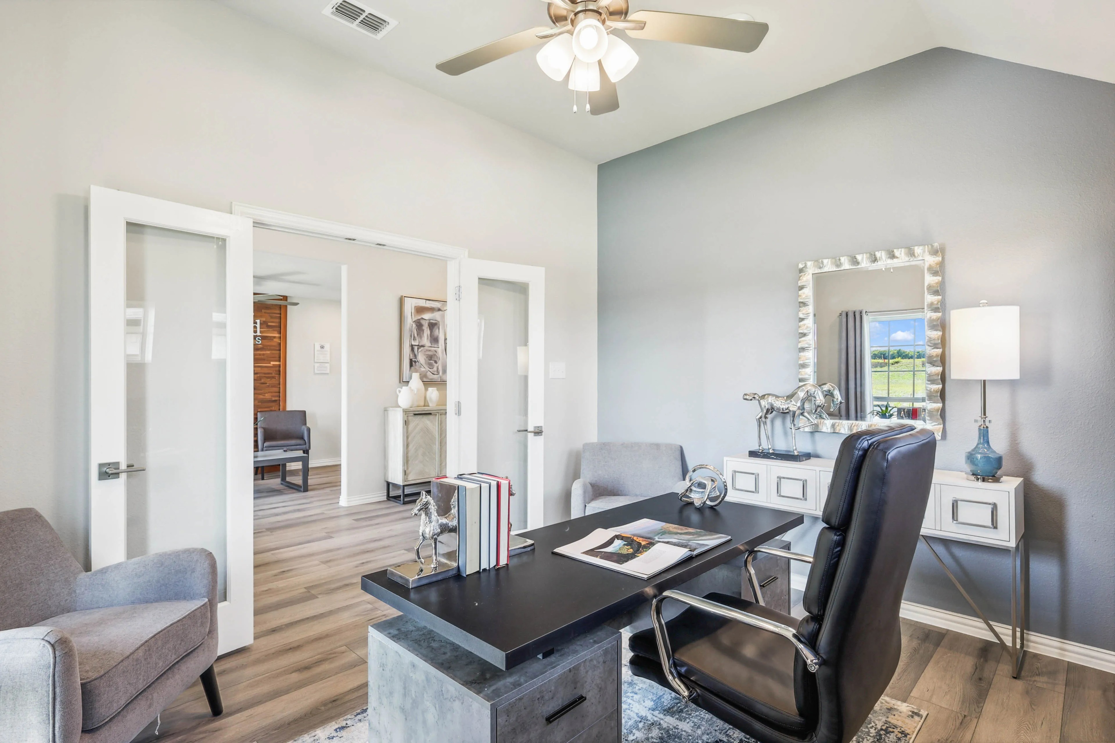 Elegant home office with modern furniture, glass French doors, and wood flooring in Pebblebrook community.