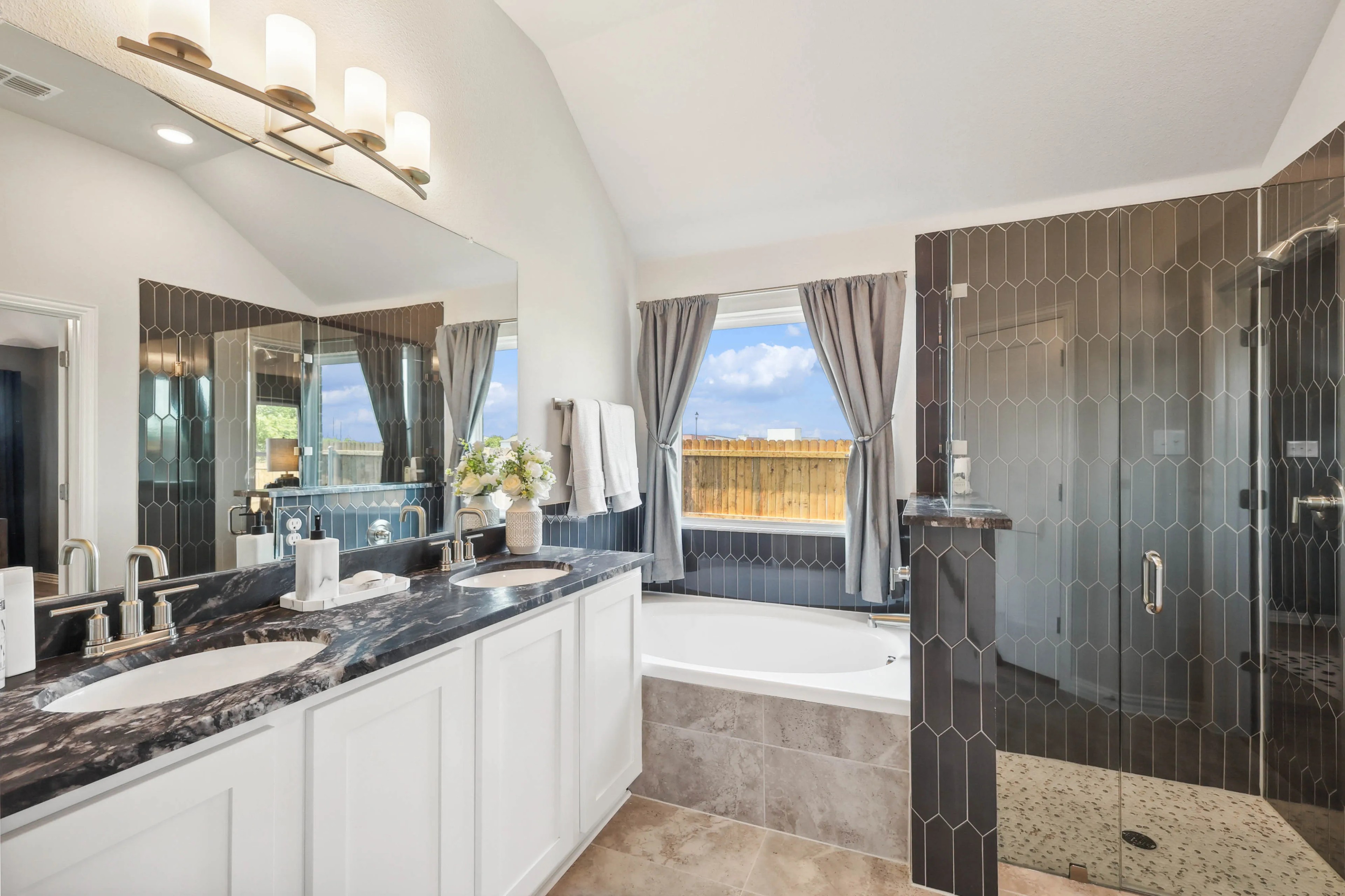 Luxurious bathroom with dual sinks, marble countertop, large mirror, glass shower in Pebblebrook community.