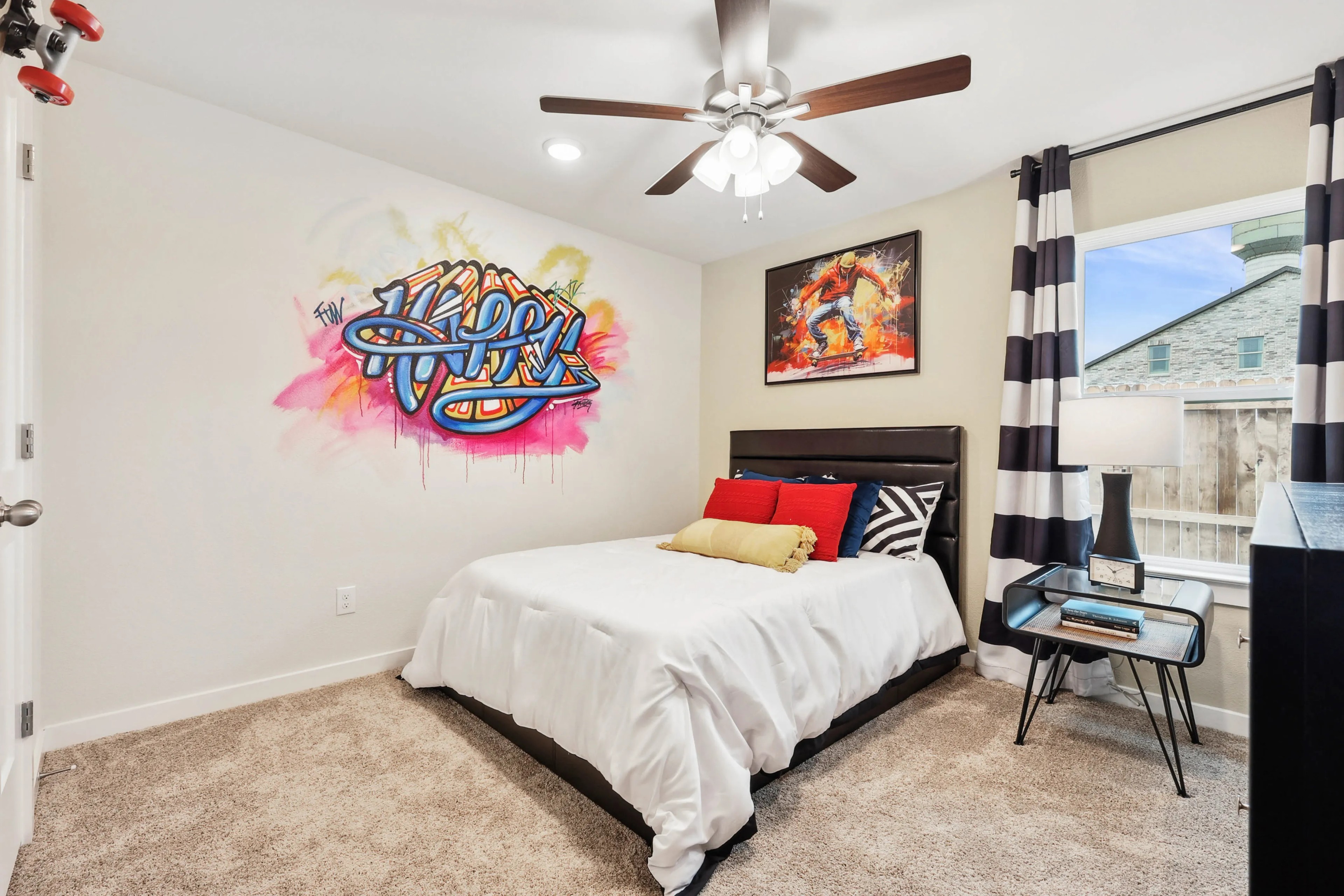 Bedroom with graffiti art, ceiling fan, striped curtains, modern decor in Simpson Crossing, cozy carpet flooring.