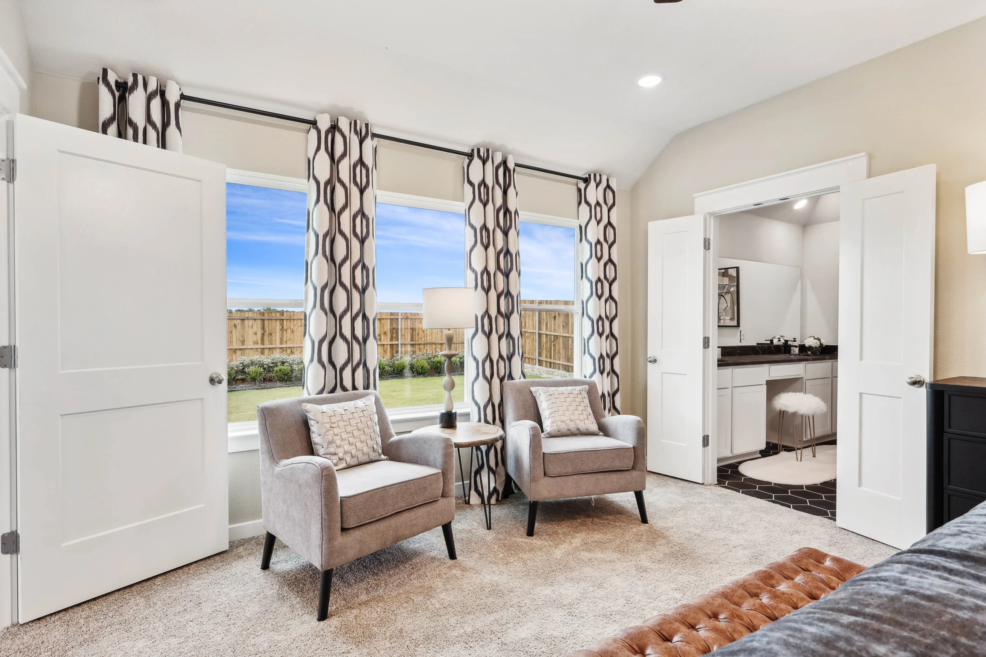 Bright living room with gray armchairs, geometric curtains, view of backyard, Simpson Crossing.