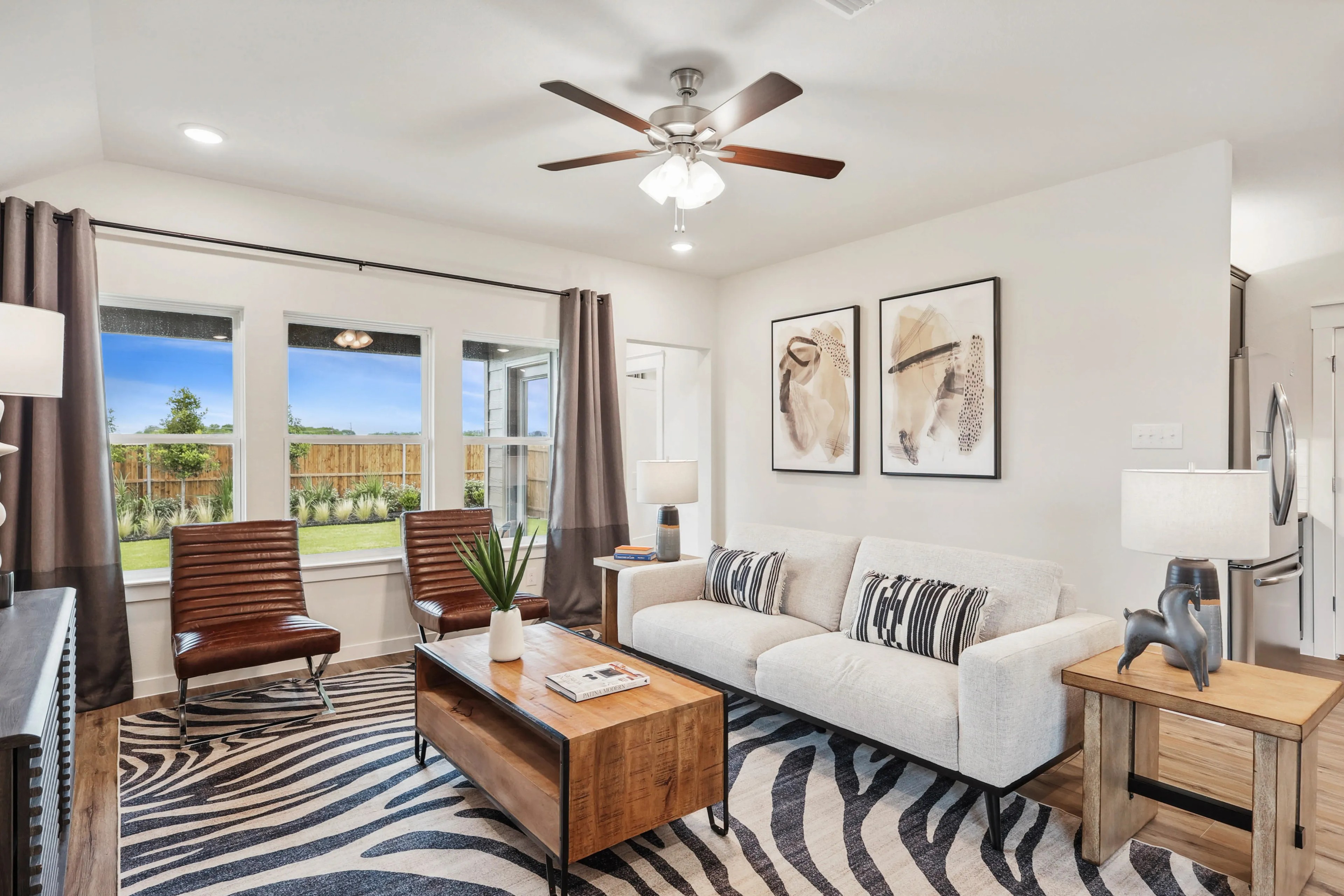 Modern living room with beige sofa, zebra rug, abstract art, wood accents, and large windows in Simpson Crossing.