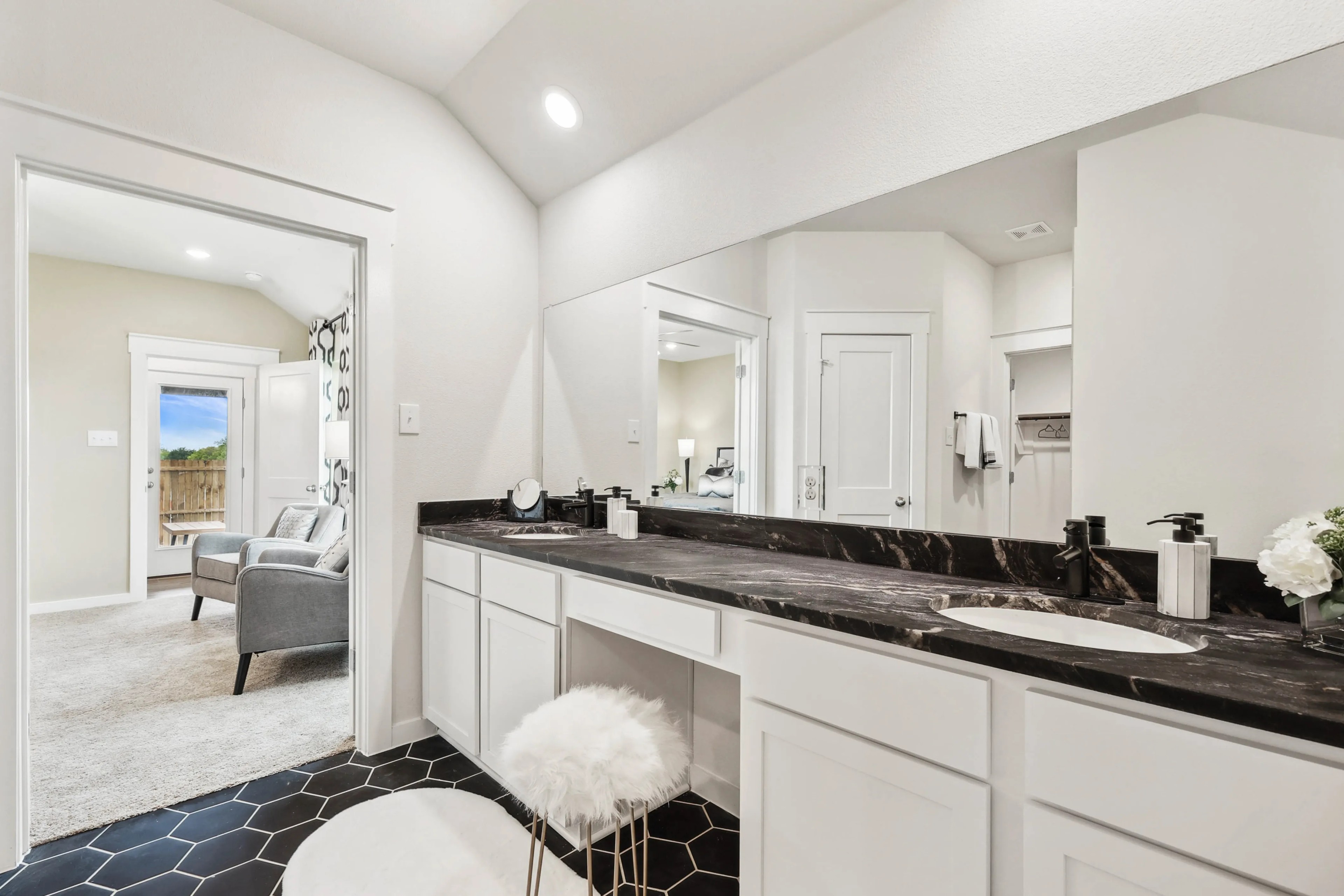 Modern bathroom with black marble countertop, hexagonal tiles, and bright lighting in Simpson Crossing community.