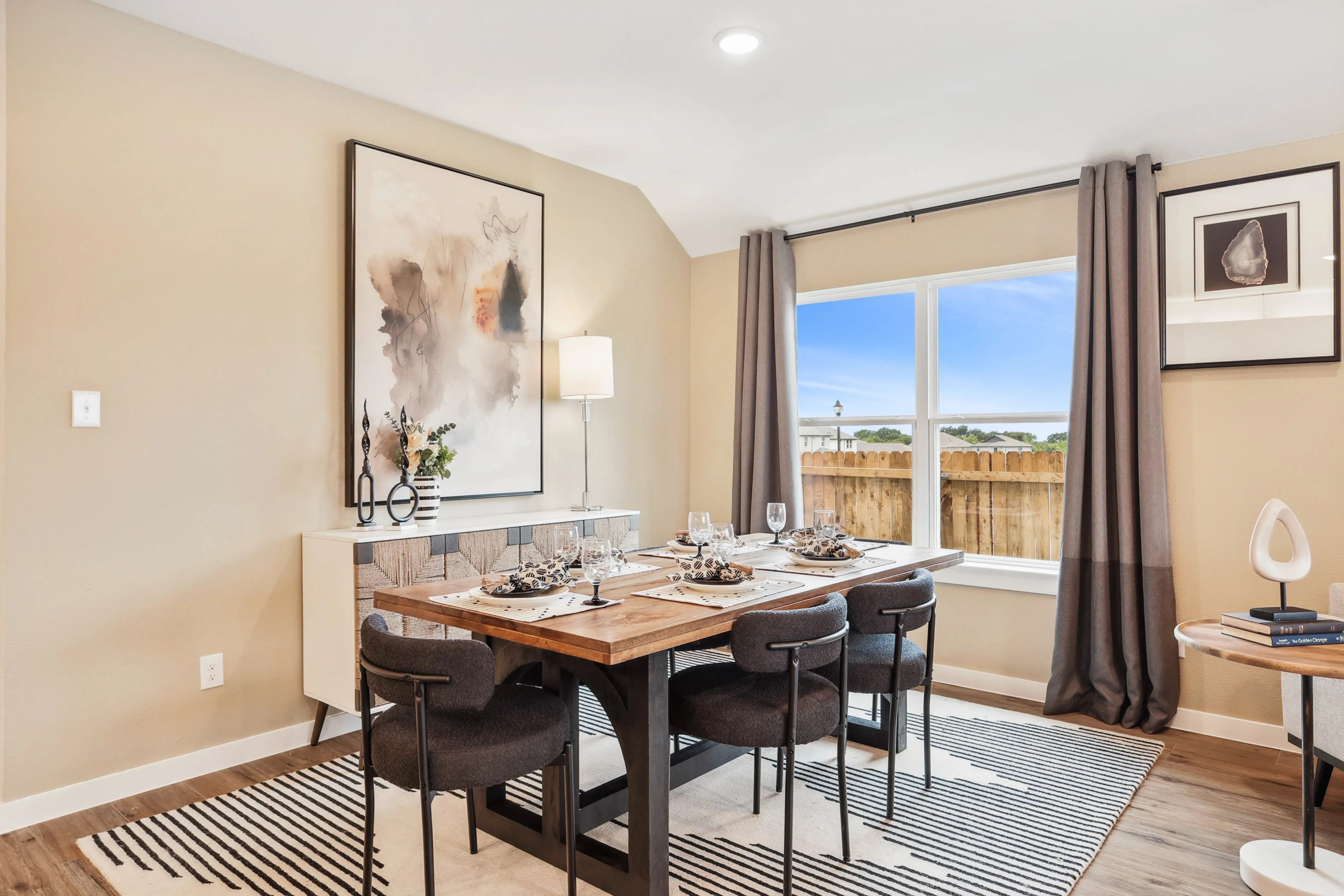 Elegant dining room with modern furniture, abstract art, large window in Simpson Crossing community.