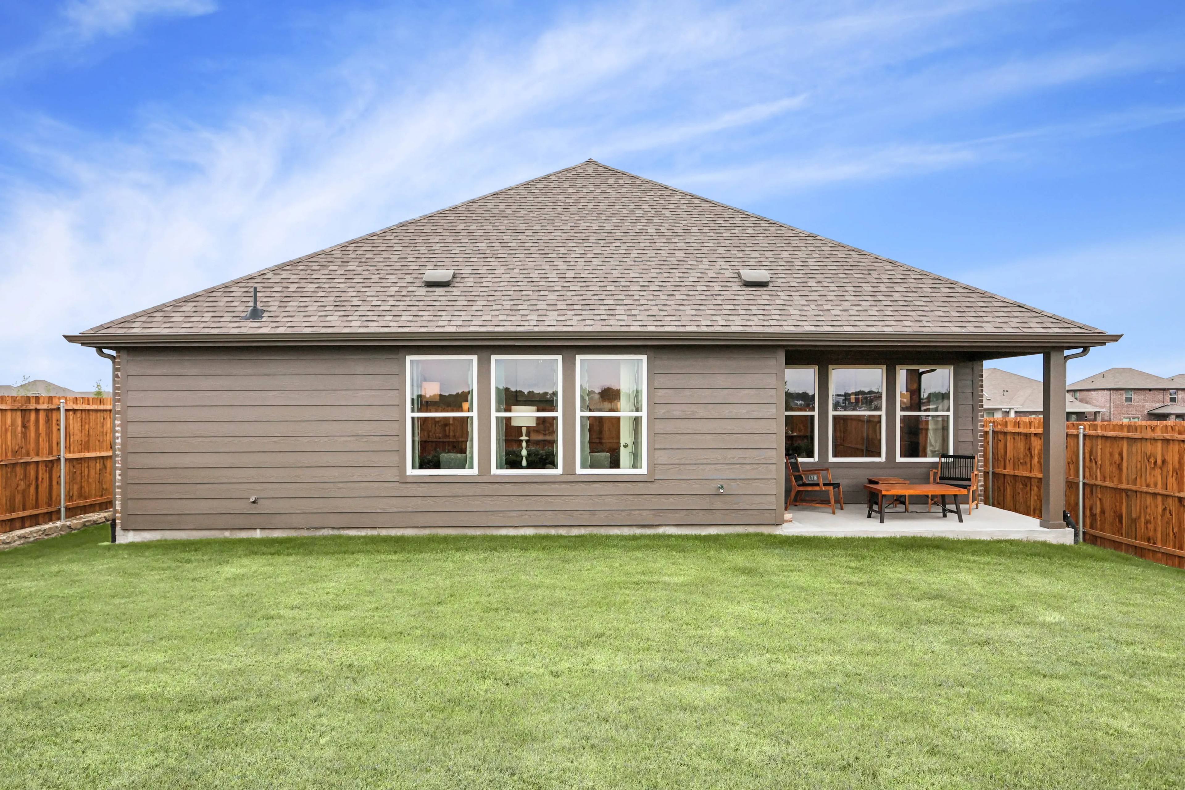 Modern single-story home with gable roof, large windows, and patio in Simpson Crossing community, fenced yard.