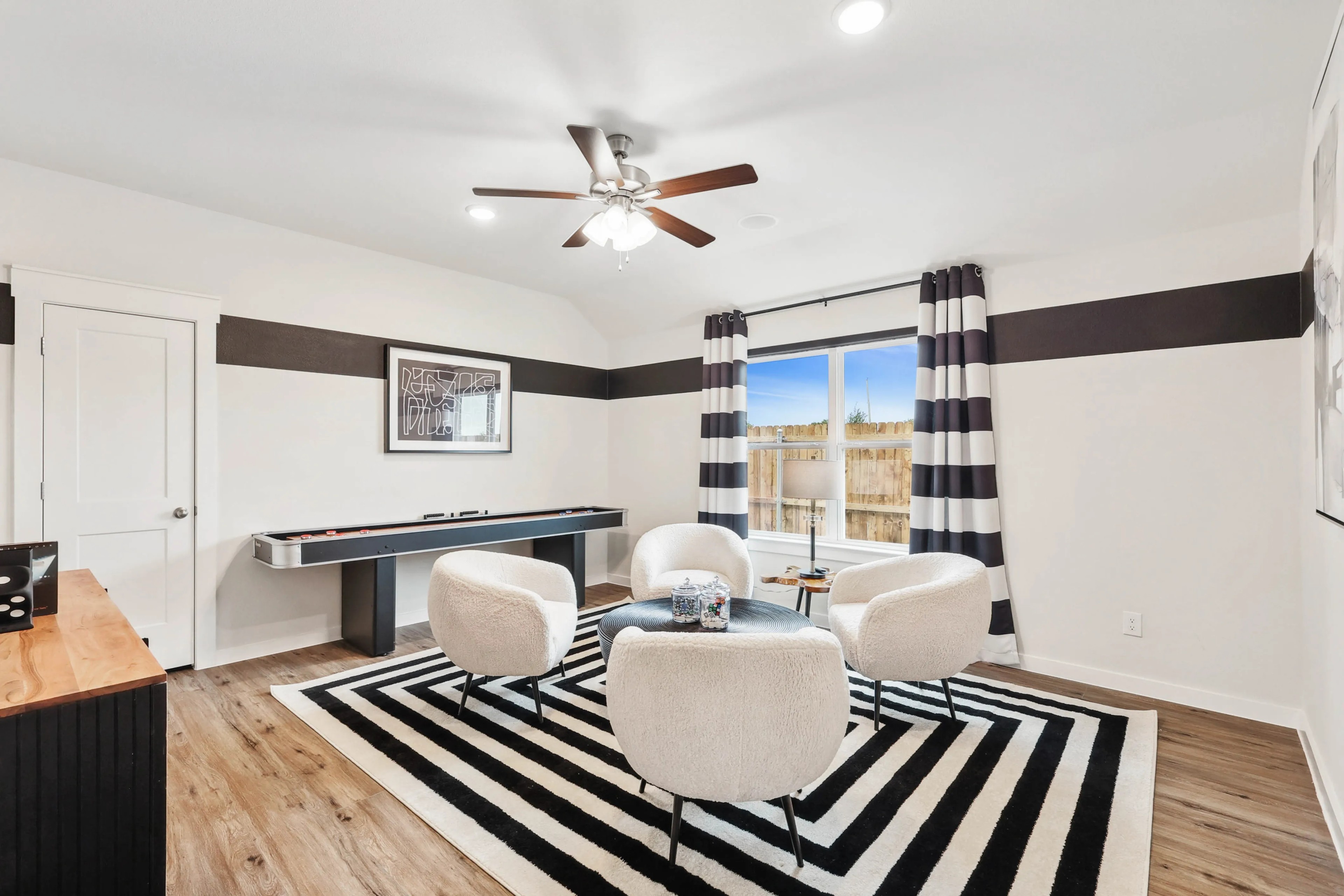 Modern living room with white chairs, striped rug, large window in Simpson Crossing.