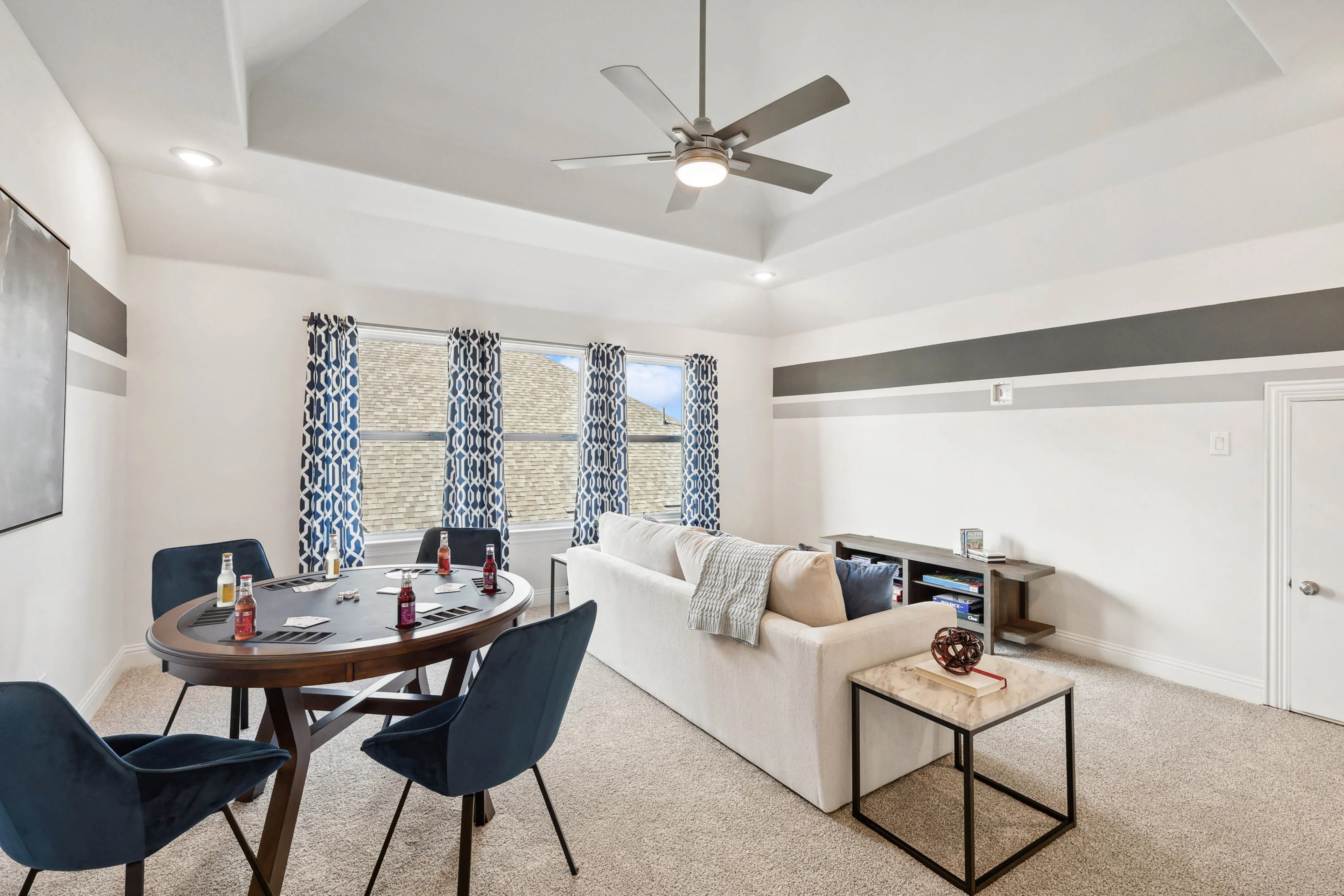 Elegant Ridge Crossing living room with poker table, blue chairs, modern ceiling fan, geometric curtains.