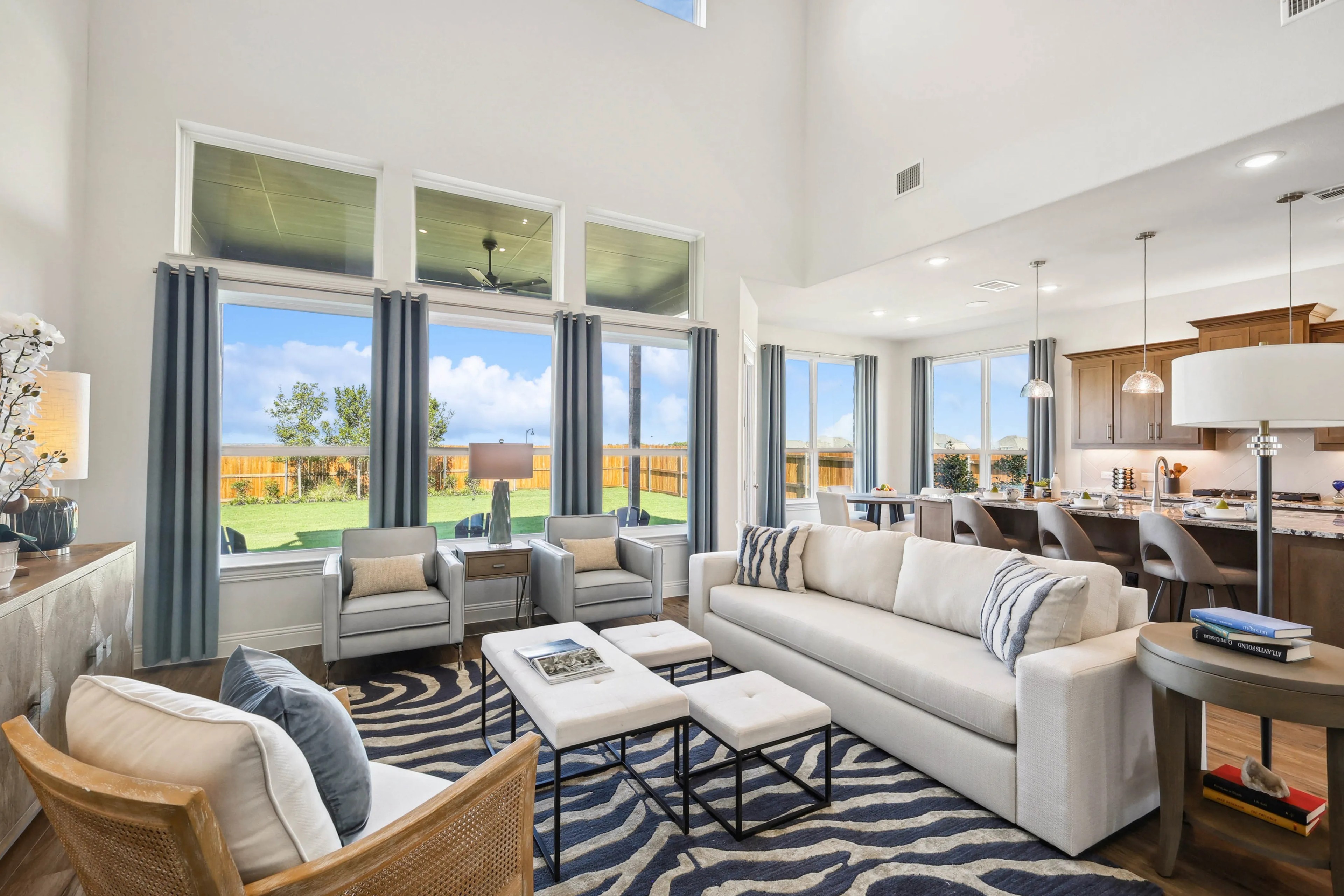 Spacious Ridge Crossing living room with tall ceilings, large windows, modern decor, and open kitchen layout.