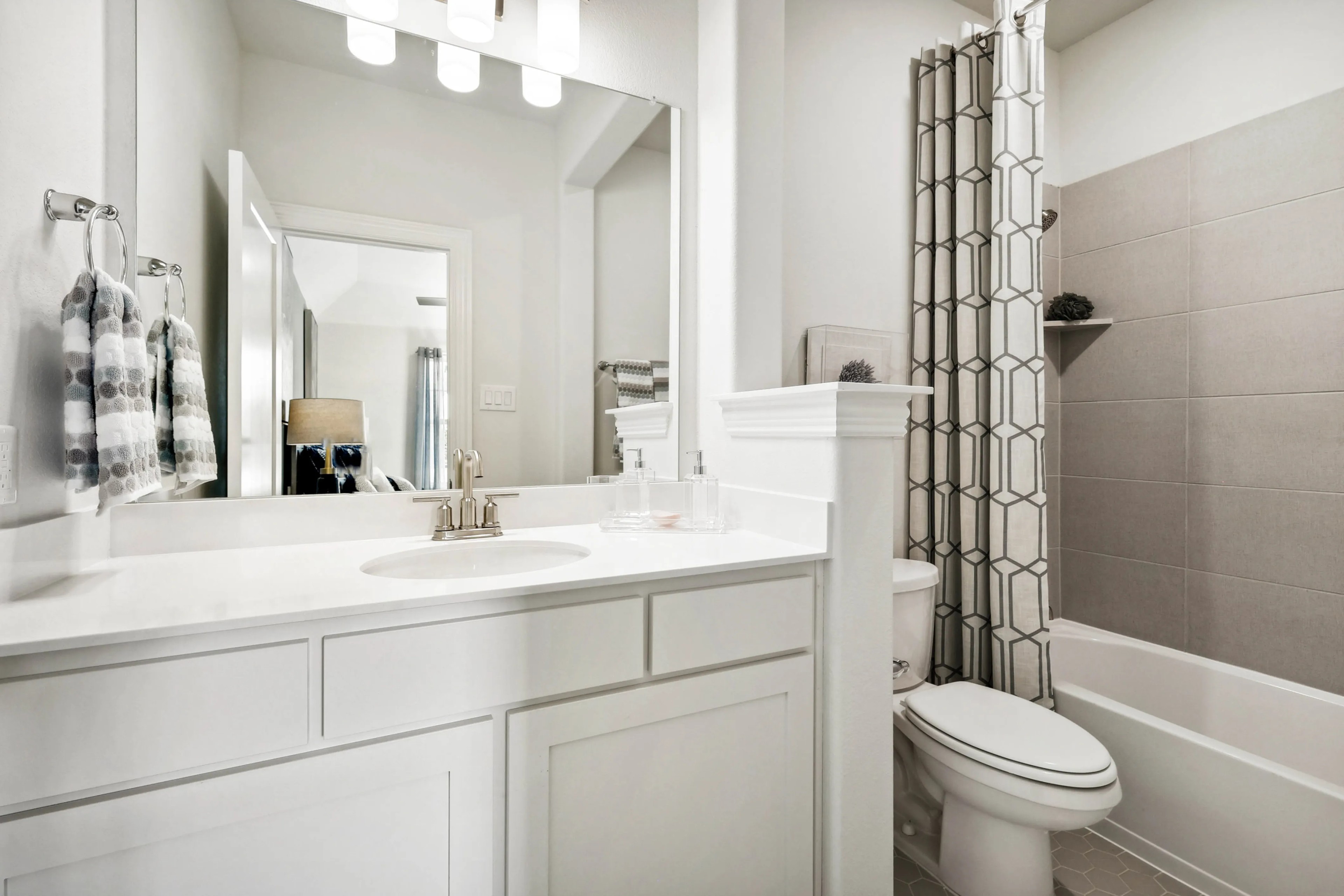 Modern bathroom with white vanity, geometric shower curtain, located in Ridge Crossing community.