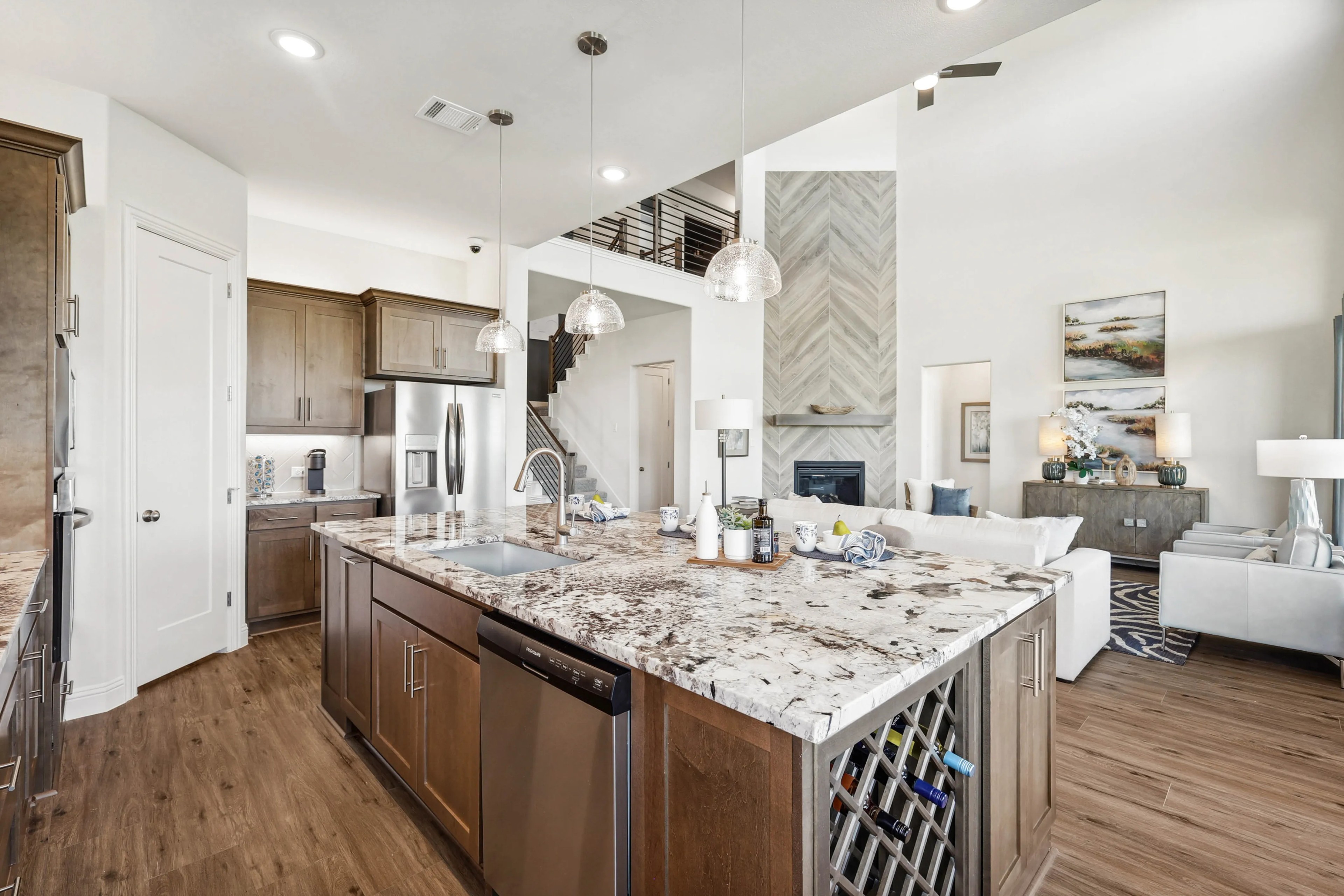 Luxurious open-concept kitchen with marble island, wood floors, Ridge Crossing home, pendant lighting.