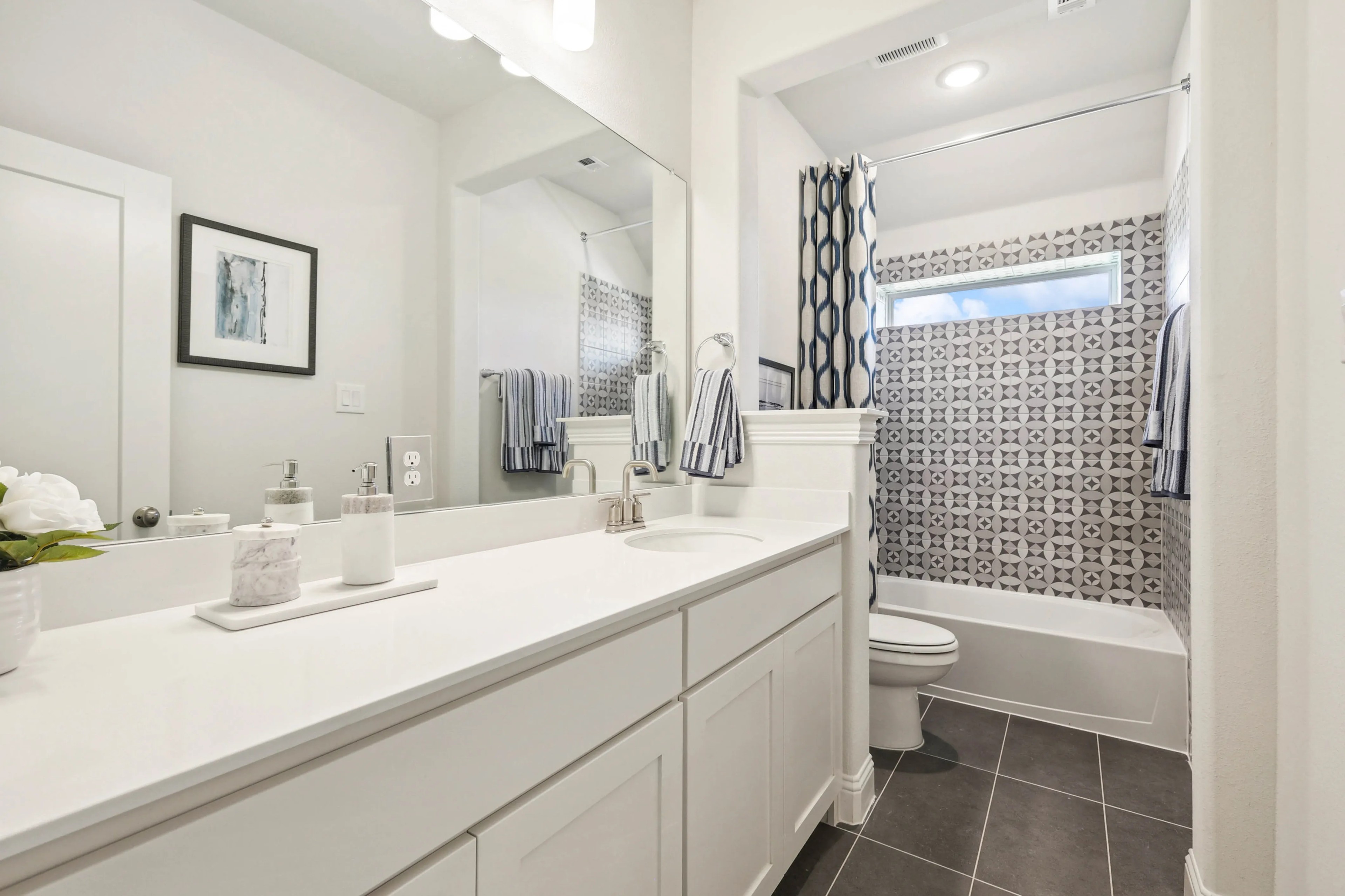 Modern bathroom with geometric tile, sleek vanity, and large mirror. Ridge Crossing community.