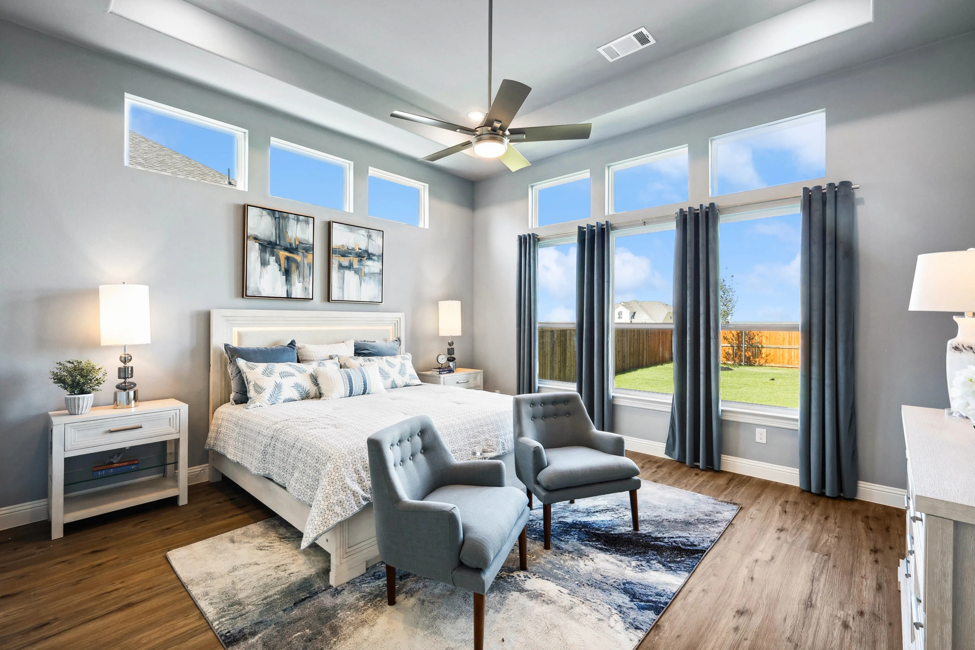 Modern bedroom with high windows, hardwood floors, and stylish decor in Ridge Crossing community.
