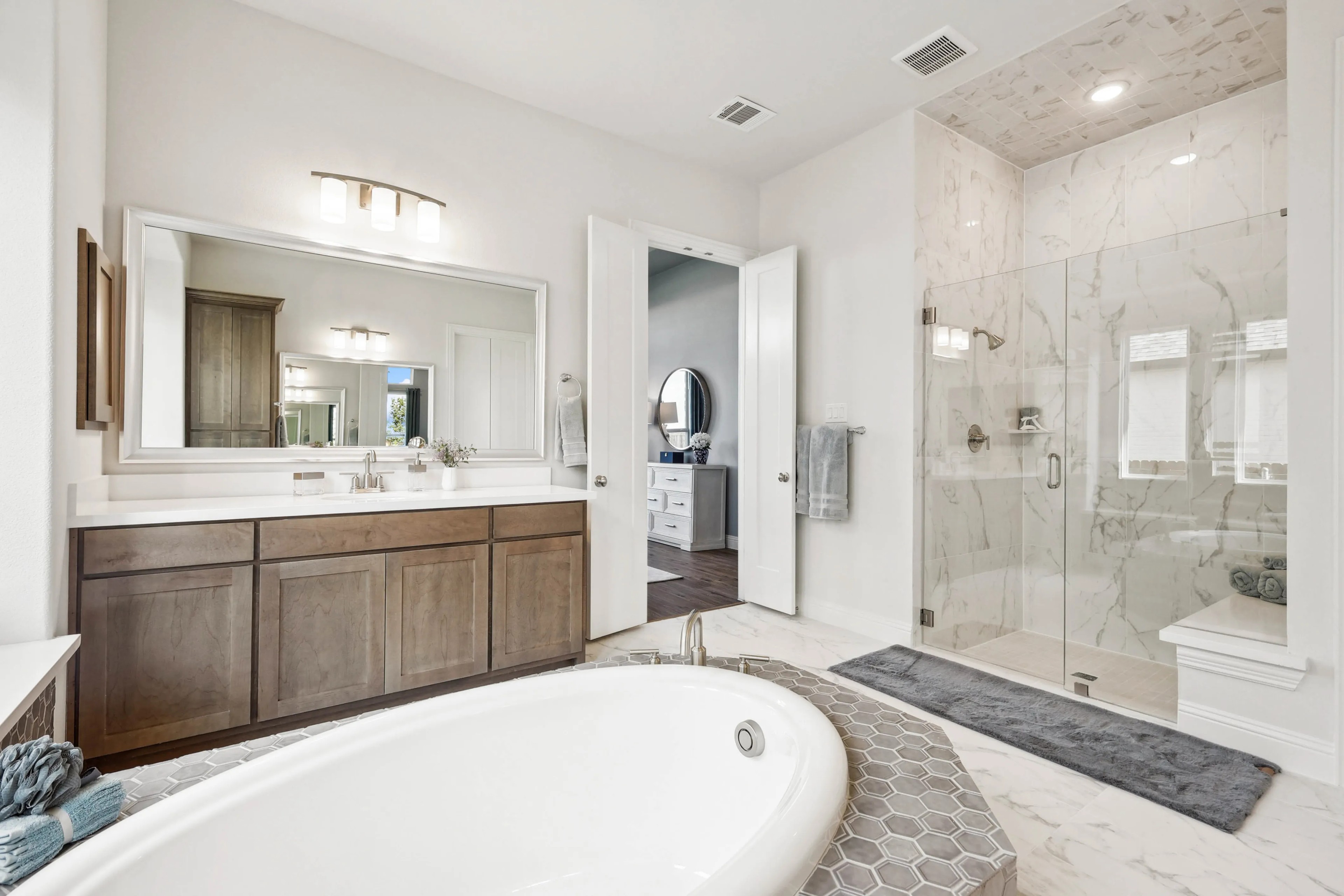 Luxurious bathroom with marble shower, freestanding tub, and wooden vanity in Ridge Crossing community.