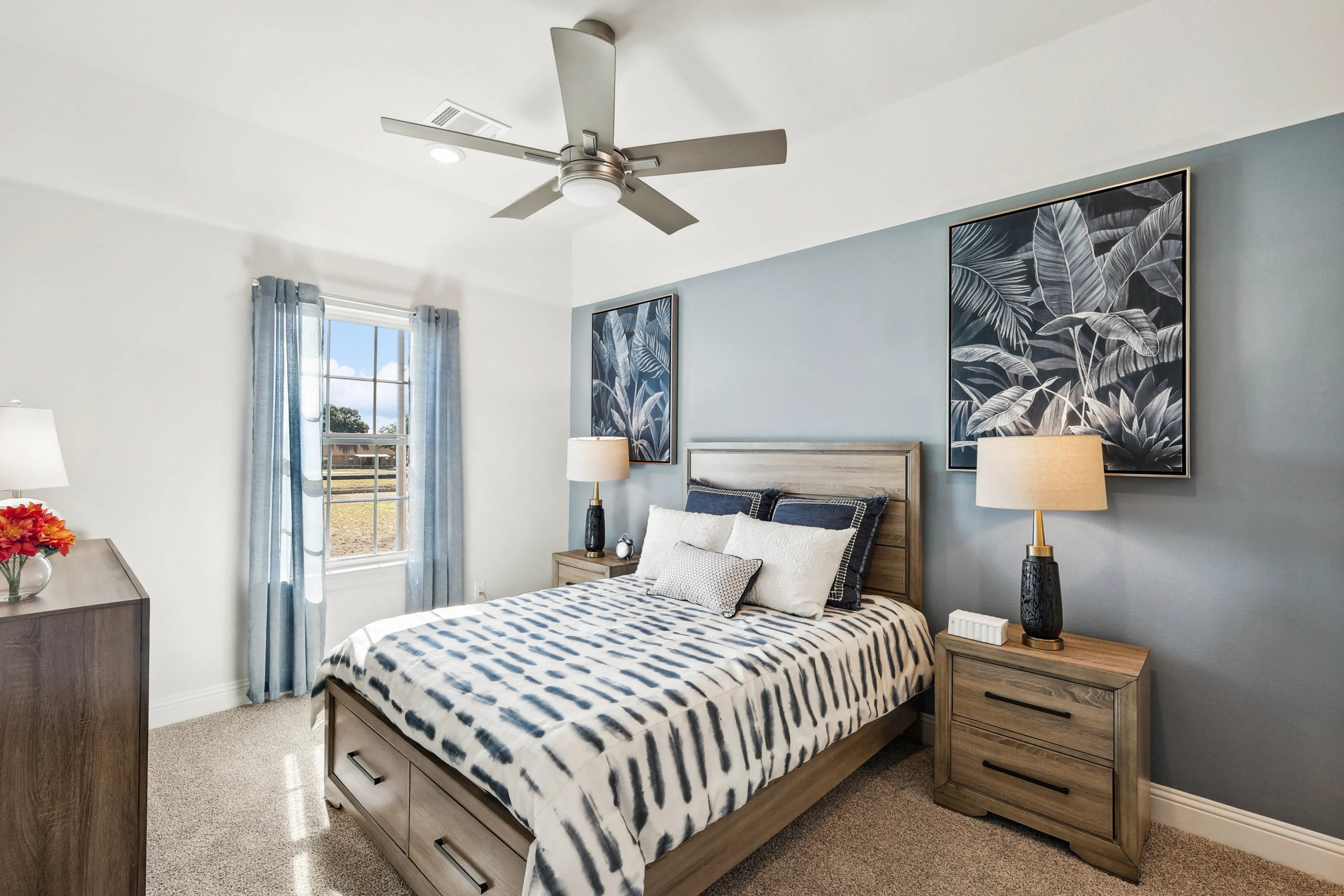 Stylish Ridge Crossing bedroom with modern decor, large window, wooden furniture, blue accents, ceiling fan.