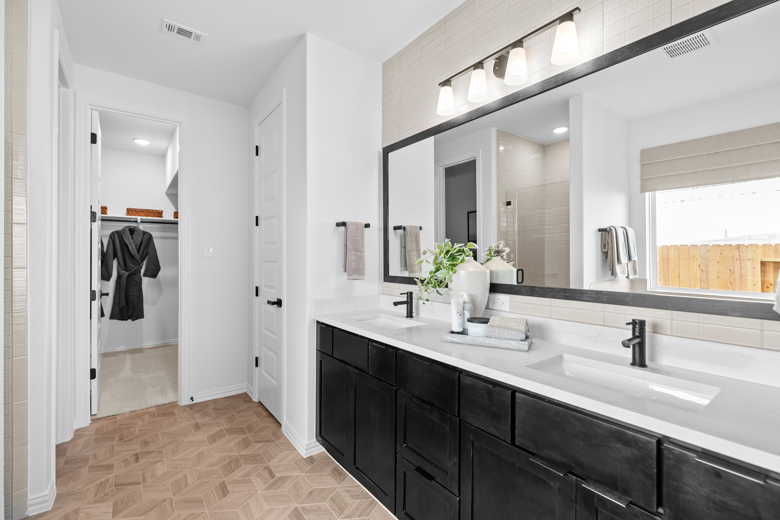 Modern bathroom with black cabinets, geometric flooring, in River Ranch community. Features large mirror and elegant lighting.