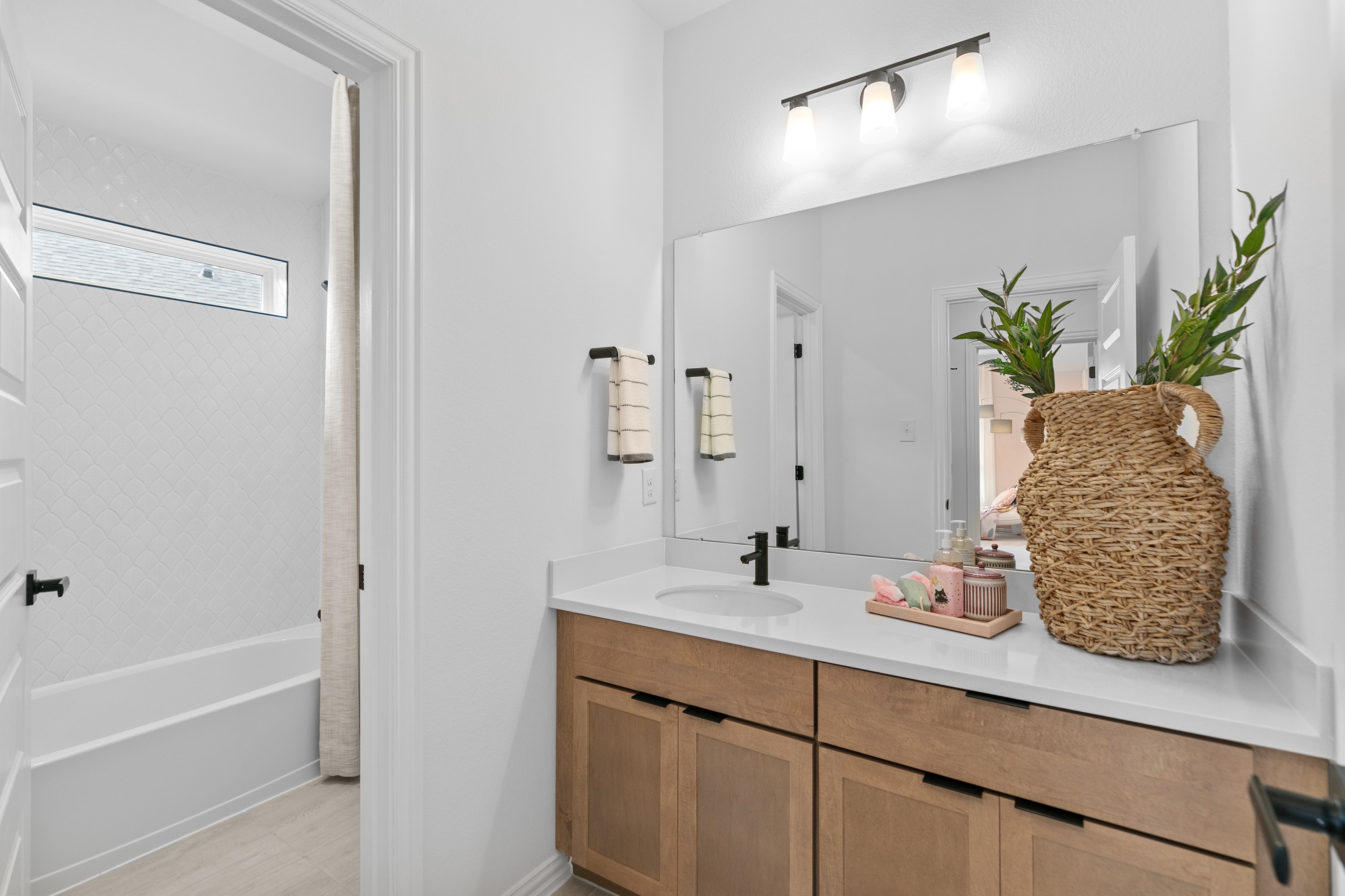 Modern bathroom in River Ranch with wood vanity, large mirror, basket decor, and tile detailing.