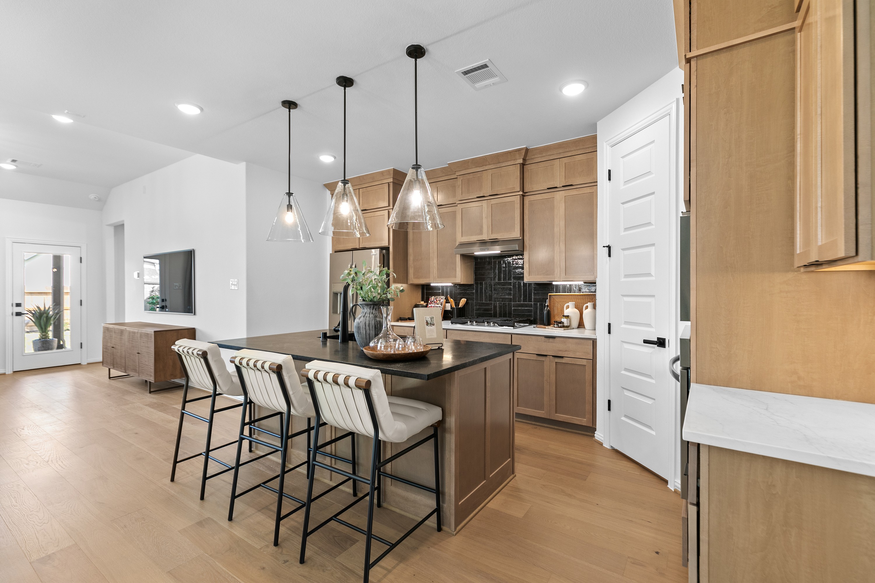 Modern kitchen in River Ranch with wood cabinets, black island, pendant lights, and door to patio.