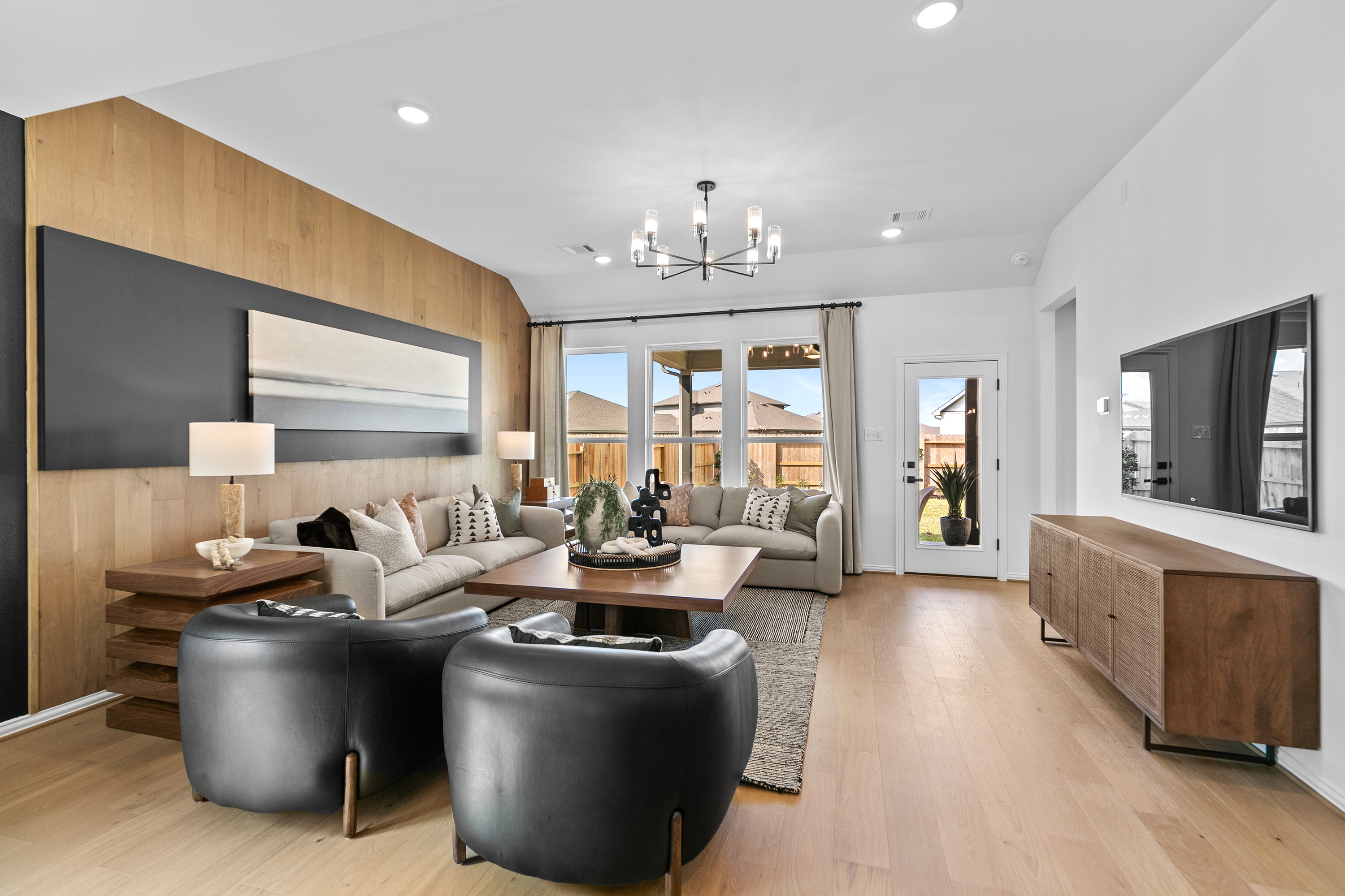Modern living room with wood accent wall, chandelier, and patio view. River Ranch location.