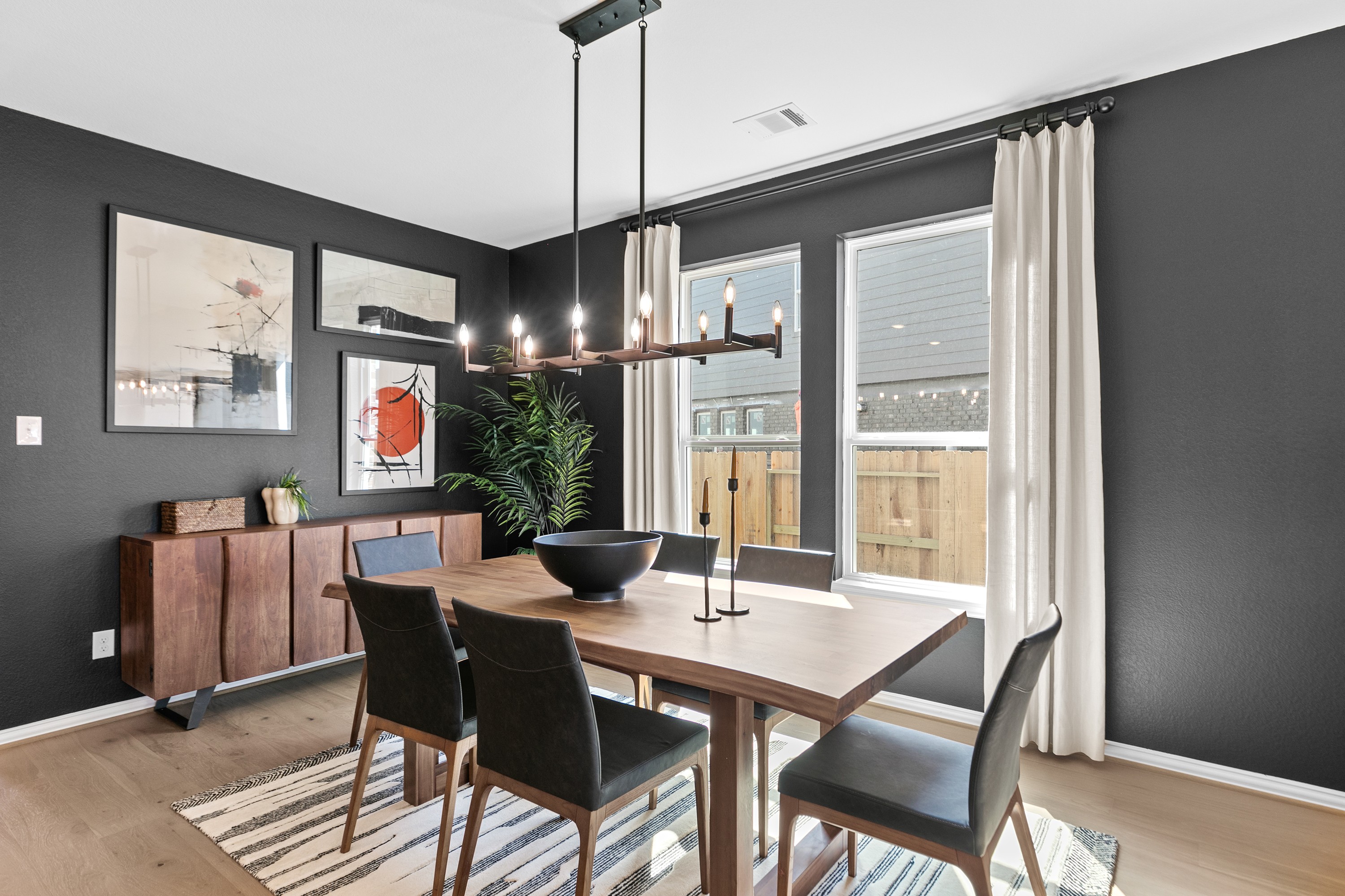 Elegant dining room, dark accent wall, modern chandelier, large windows, wood table in River Ranch.