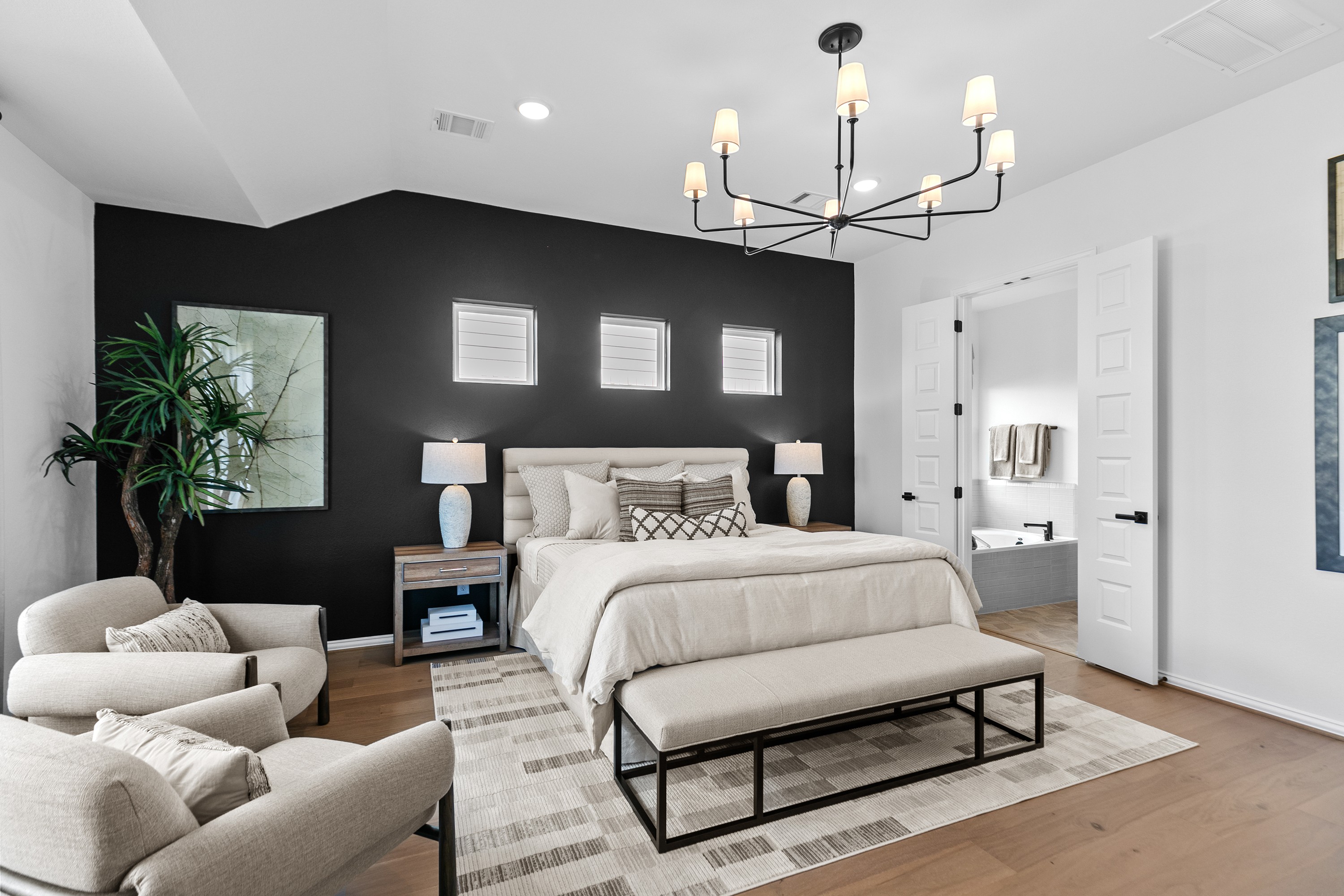 Elegant River Ranch bedroom with black accent wall, modern chandelier, and en suite door.