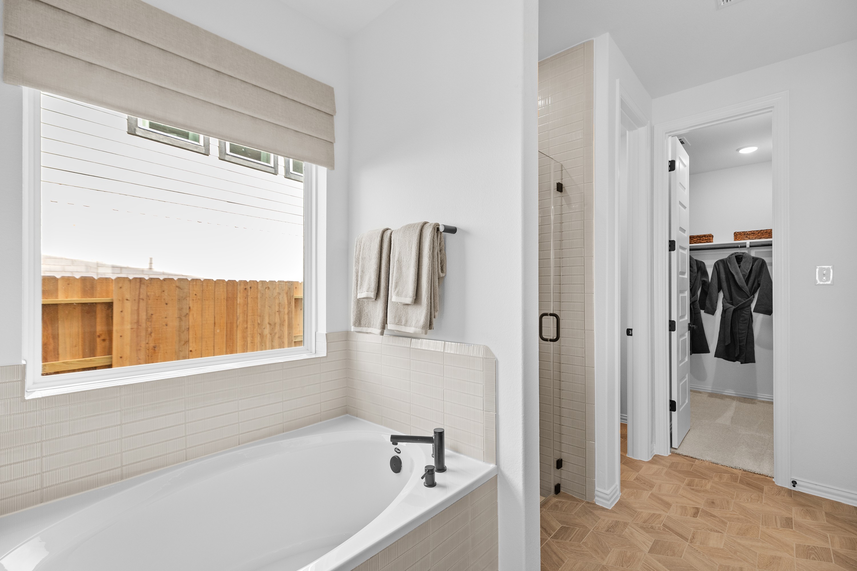 Luxurious bathroom with modern tub, glass shower, and spacious closet in River Ranch community.