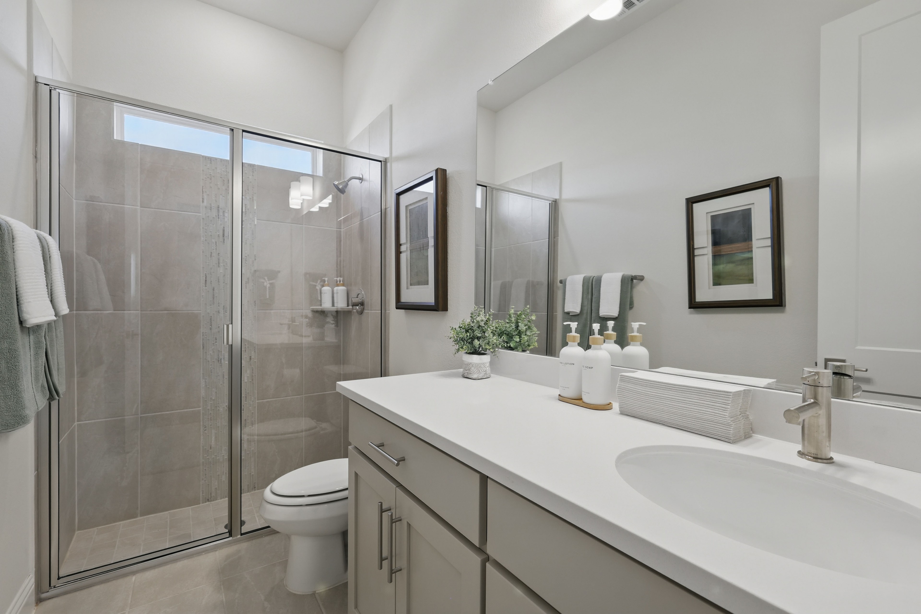 Modern bathroom in Rio Vista at Kelly Ranch, features white vanity, glass shower, minimalist decor.