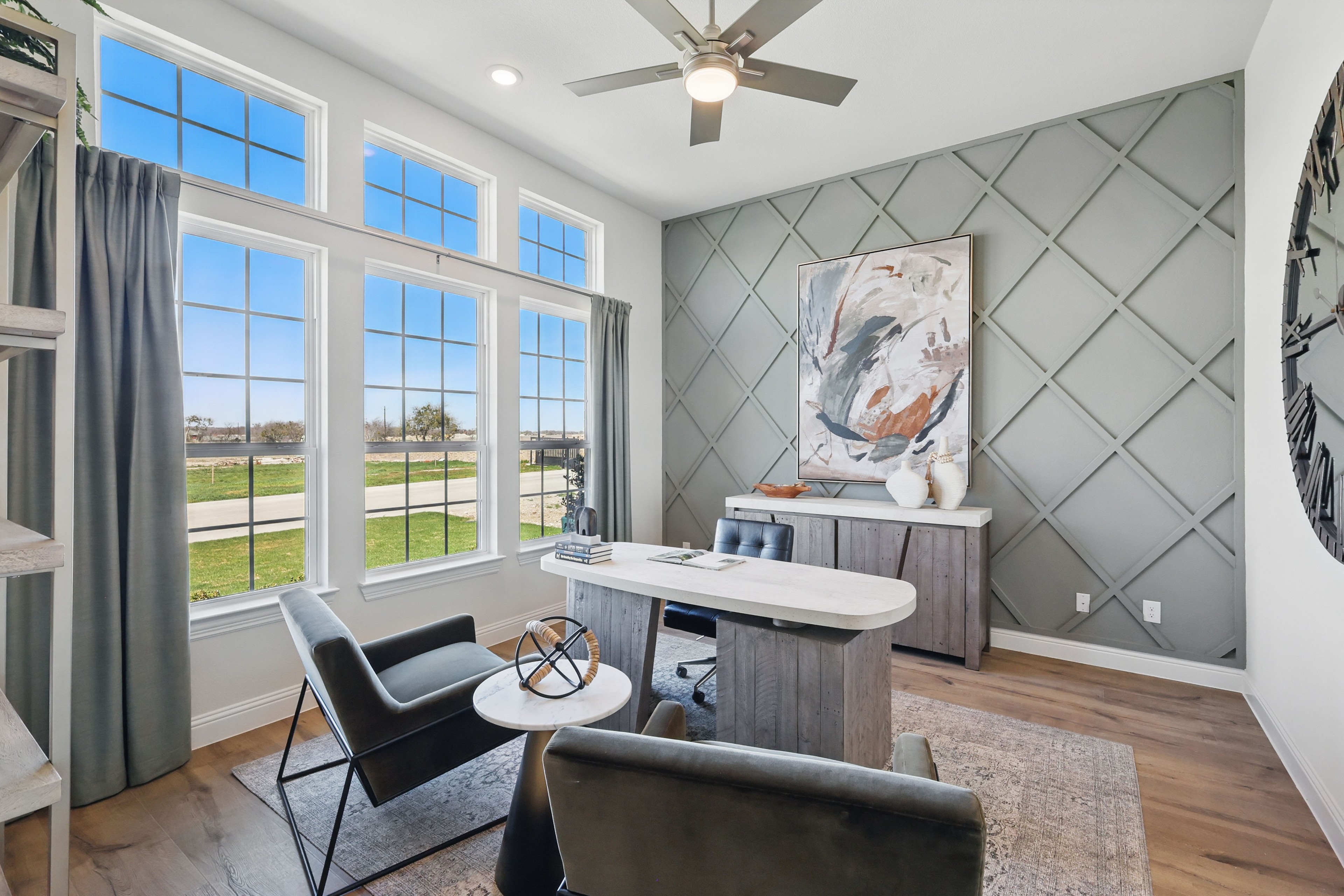 Home office with large windows, diamond-patterned accent wall, modern furniture, Rio Vista at Kelly Ranch.