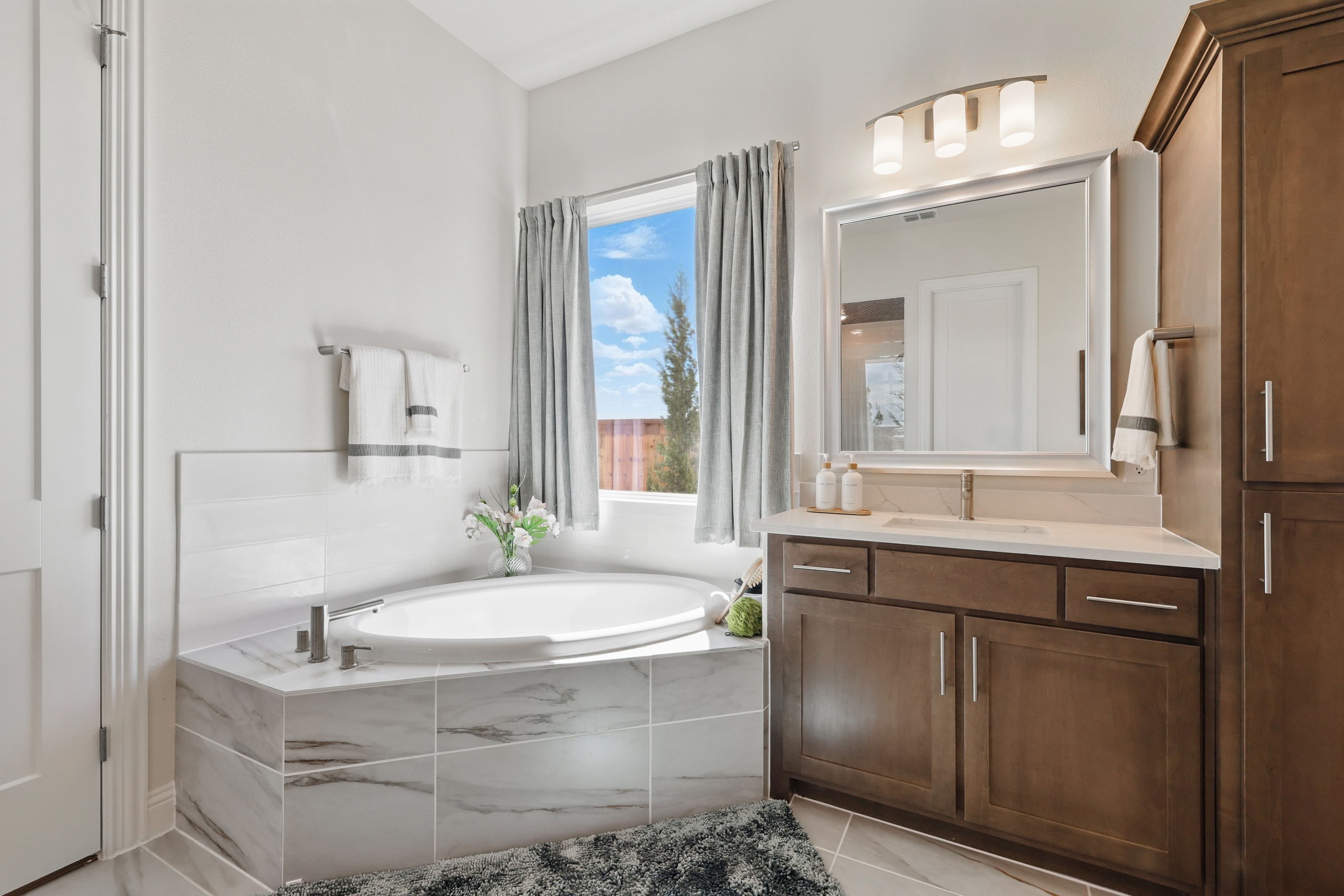 Luxury bathroom with marble tiles, wood cabinets, large window, located in Rio Vista at Kelly Ranch.