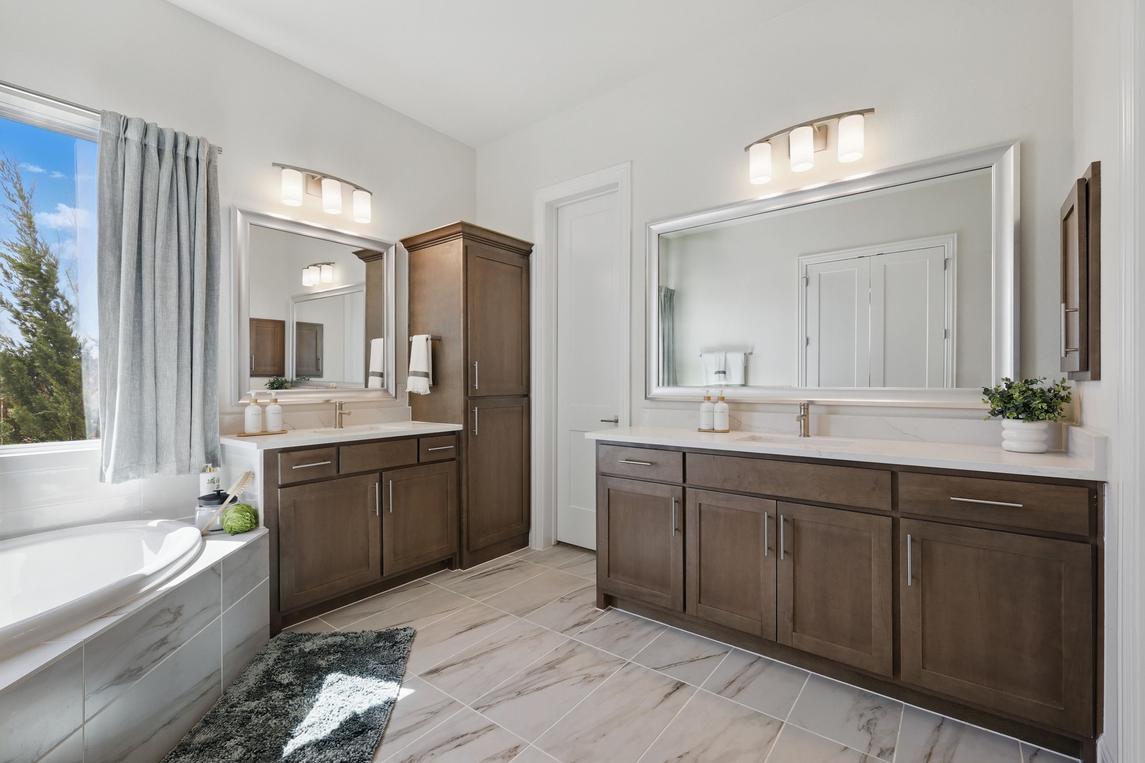 Luxurious bathroom at Rio Vista, Kelly Ranch; dual sinks, wooden cabinetry, marble tile, natural light.