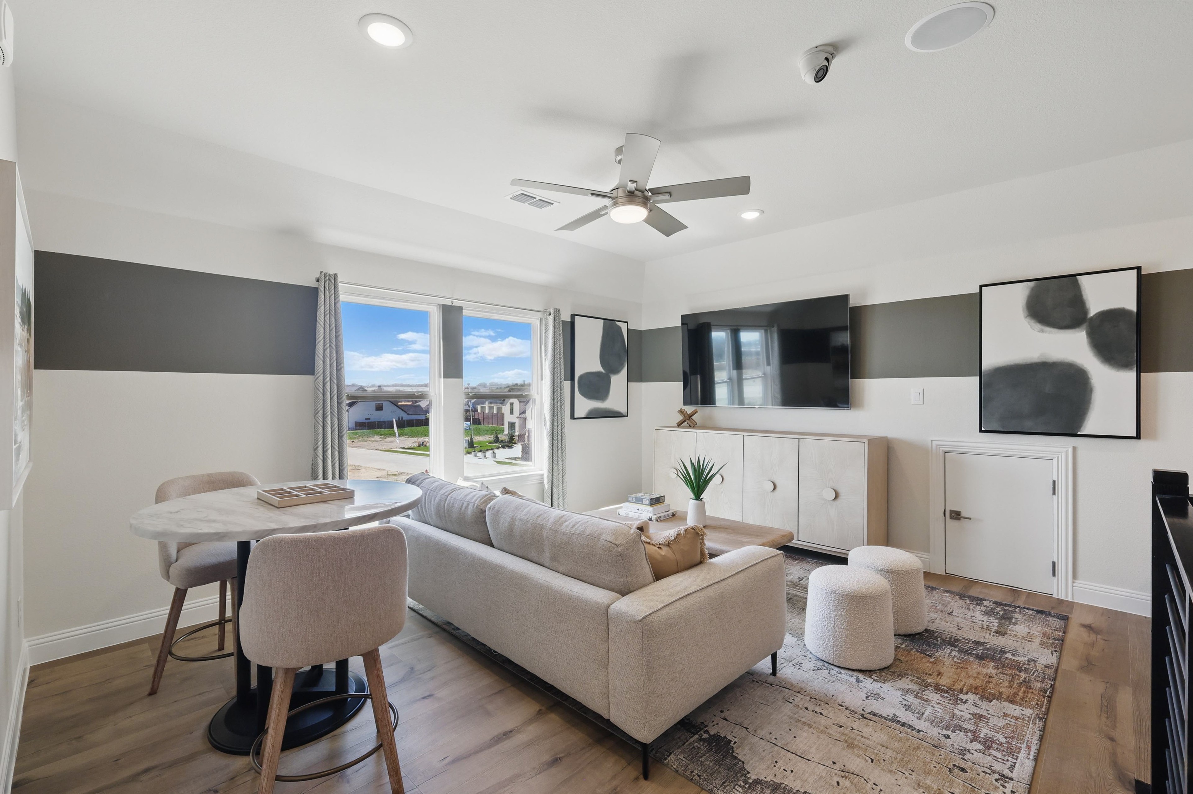Modern living room with beige sofa, marble table, TV, abstract art in Rio Vista at Kelly Ranch, scenic view.